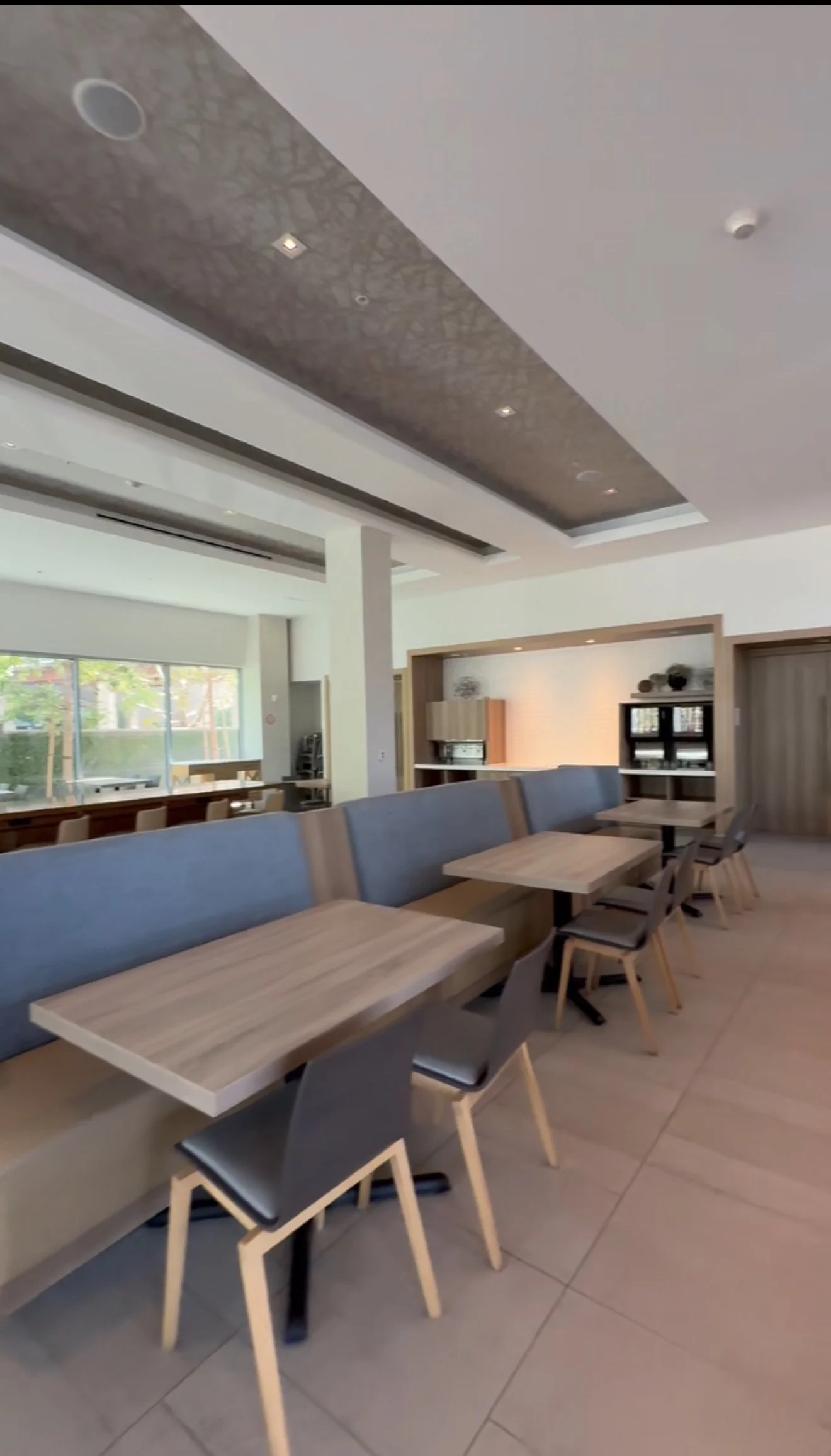Empty dining area with wooden tables, black and wooden chairs, a blue bench, and a modern design interior in a restaurant or cafe.