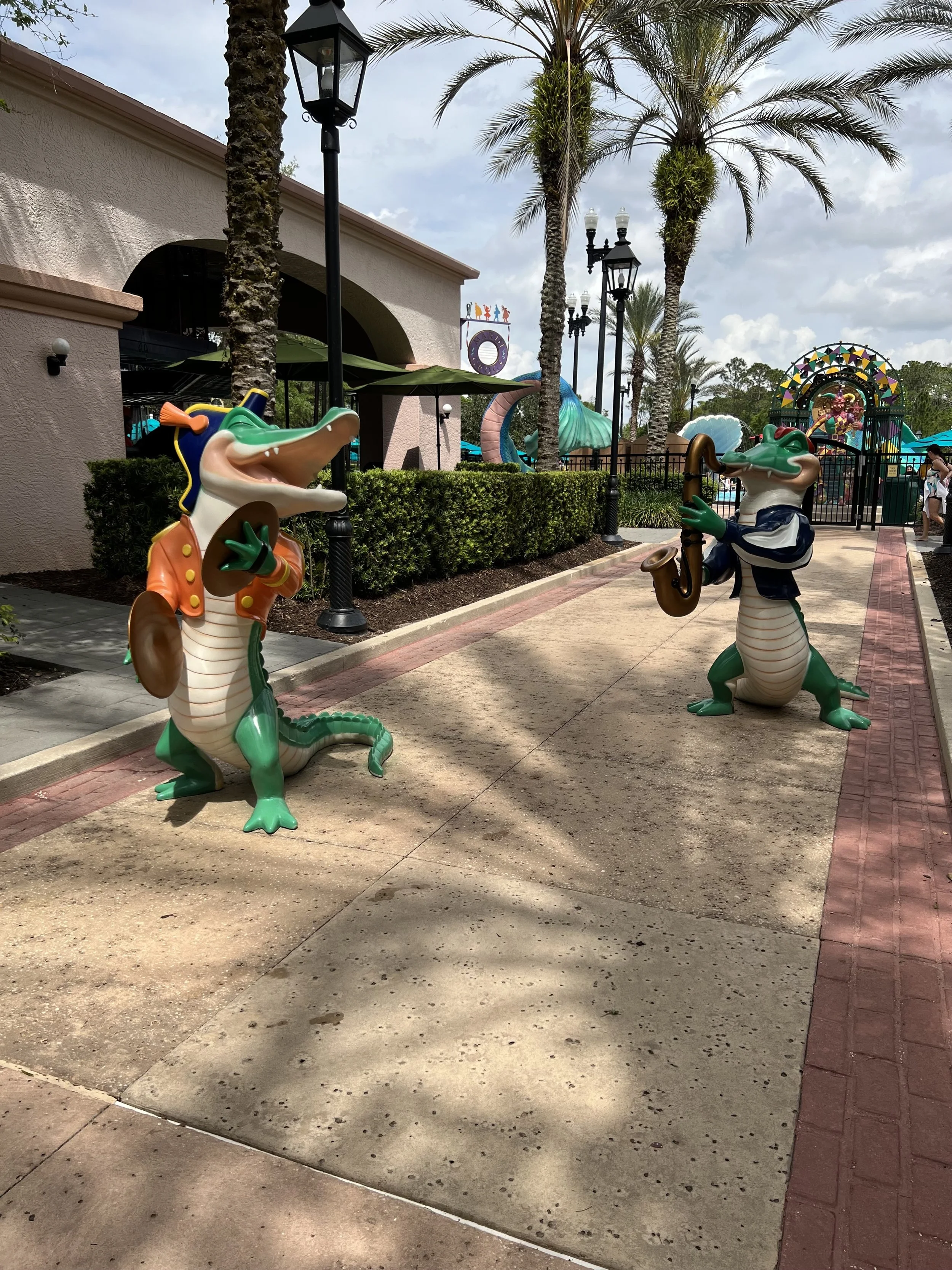 Colorful crocodile statues playing musical instruments outside at a theme park.