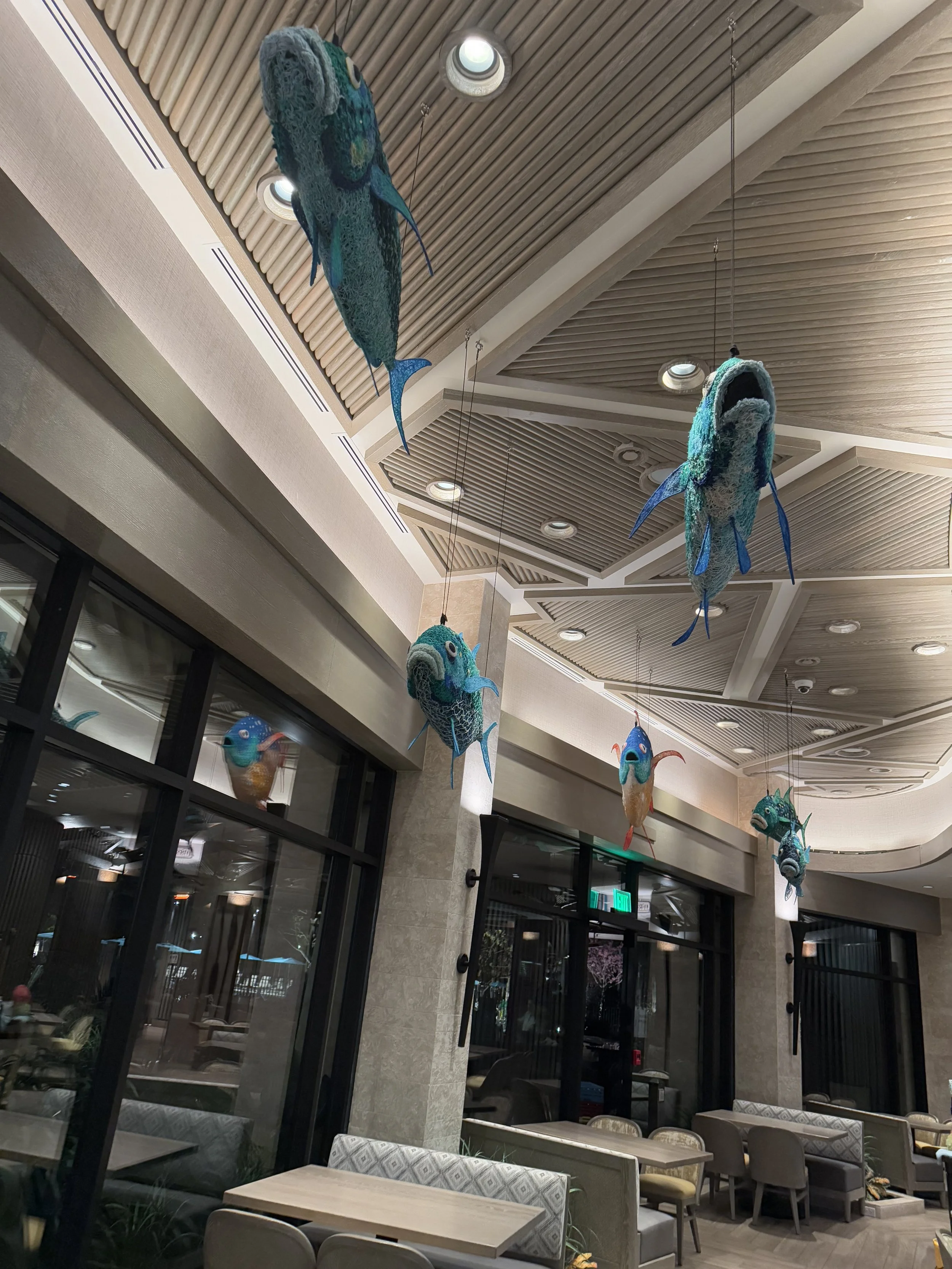 Decorative hanging fish sculptures in a modern restaurant or hotel interior.