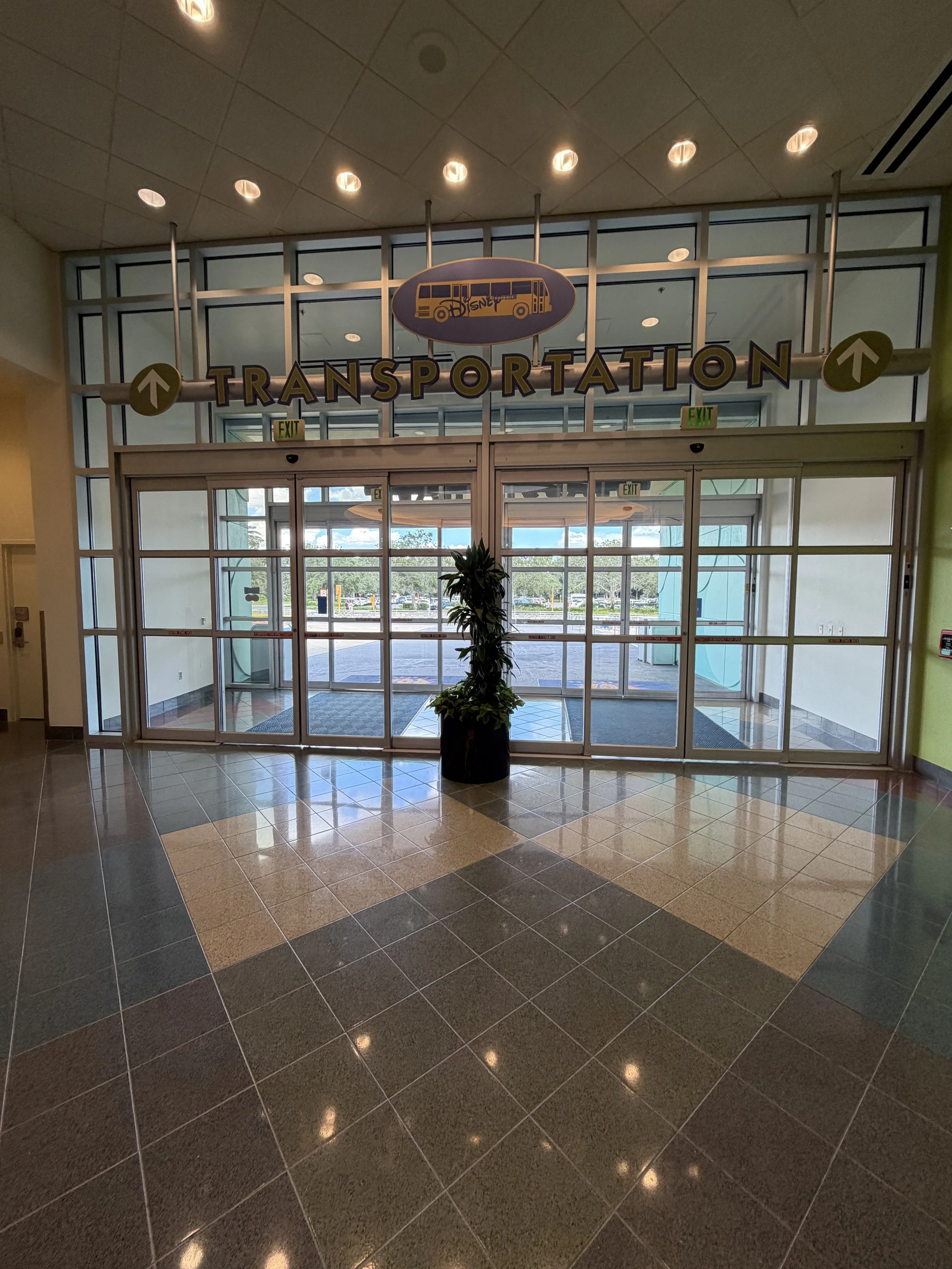 Entrance to a transportation area with glass doors, a potted plant in front, and signs for loading and unloading bays.