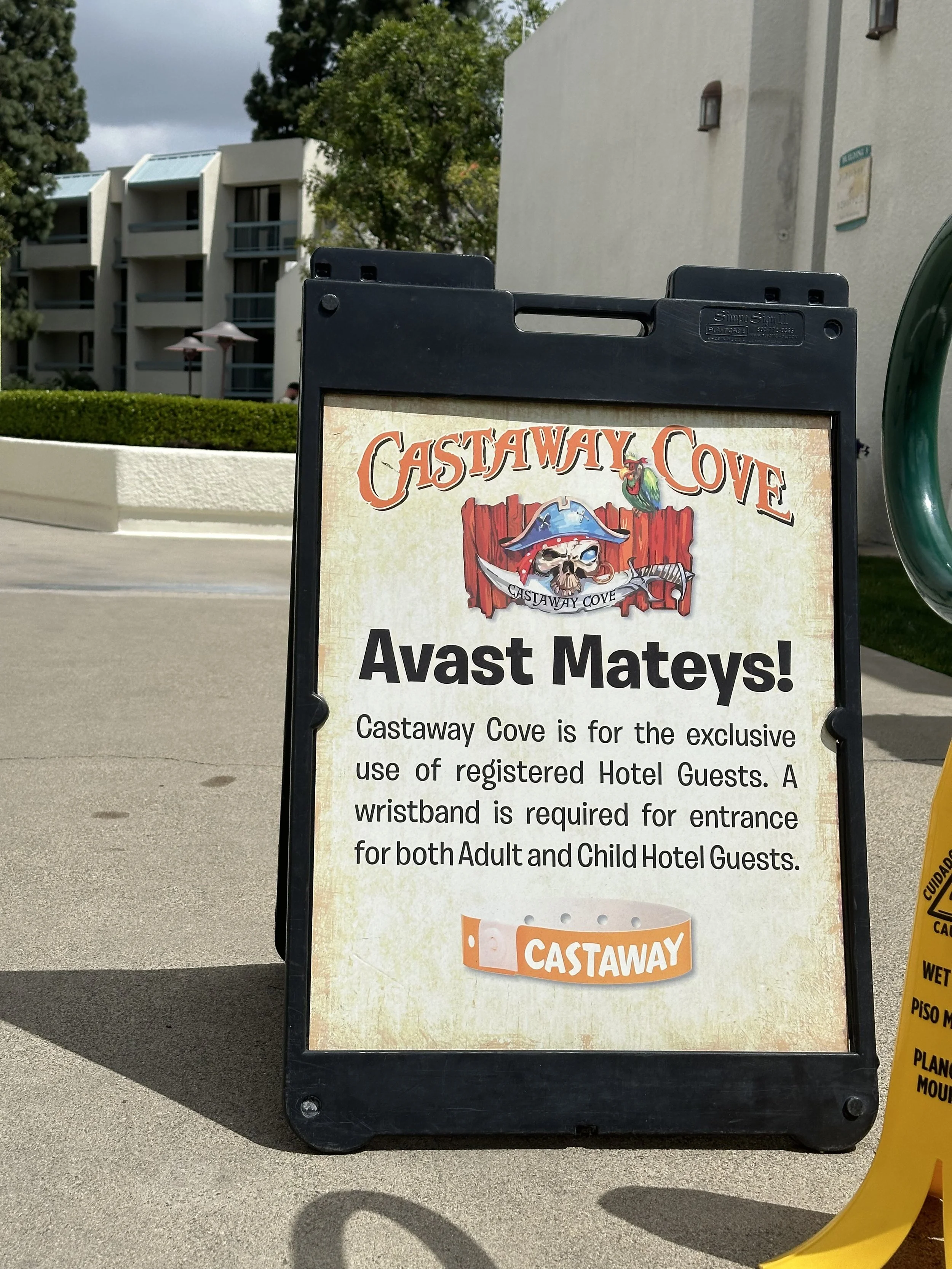Signboard for Castaway Cove with a pirate skull logo and a wristband requirement notice for hotel guests.