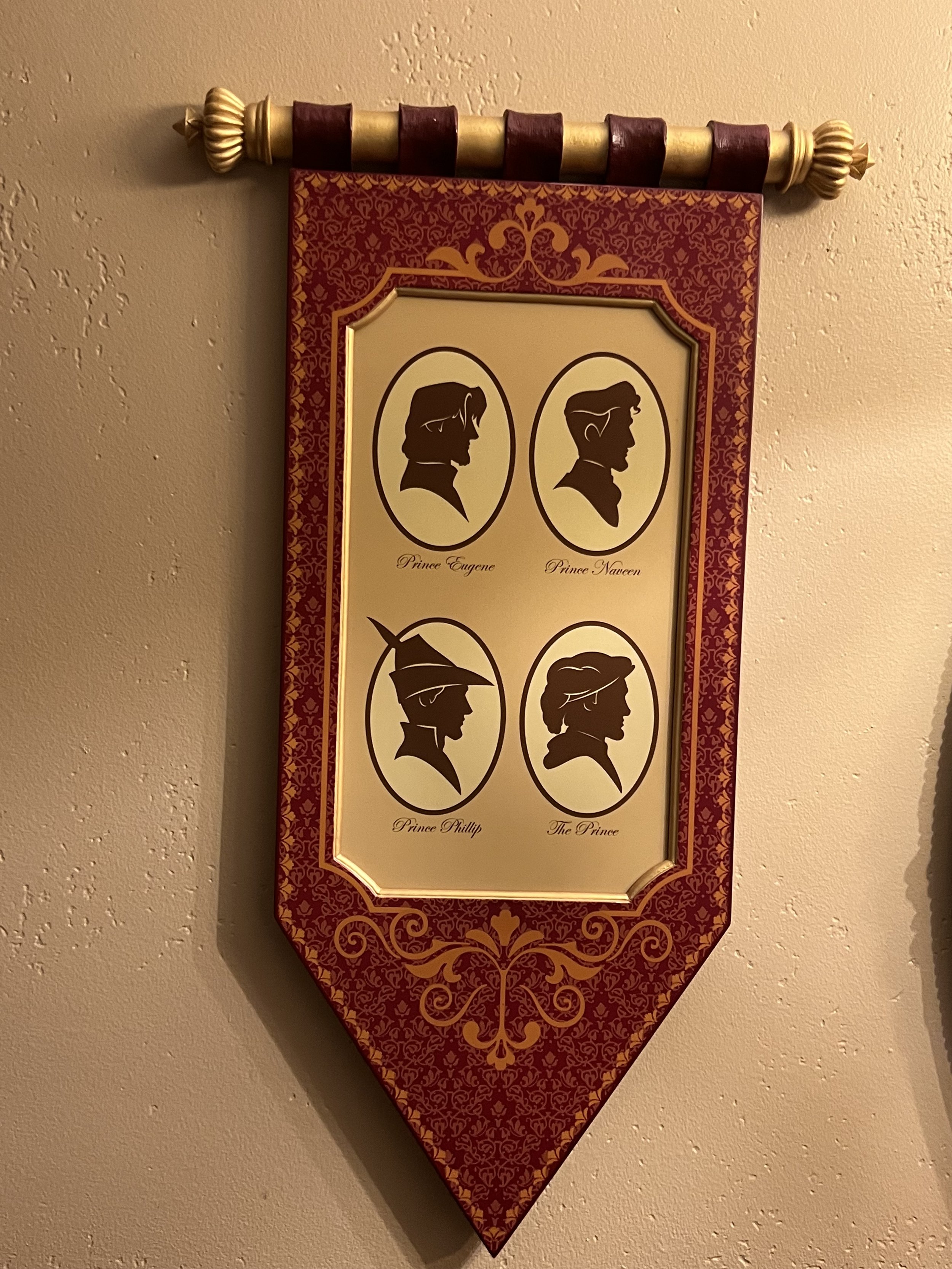 A decorative wall hanging featuring four black silhouette portraits of princes in oval frames, labeled as Prince Eugene, Prince Naveen, Prince Phillip, and The Prince.