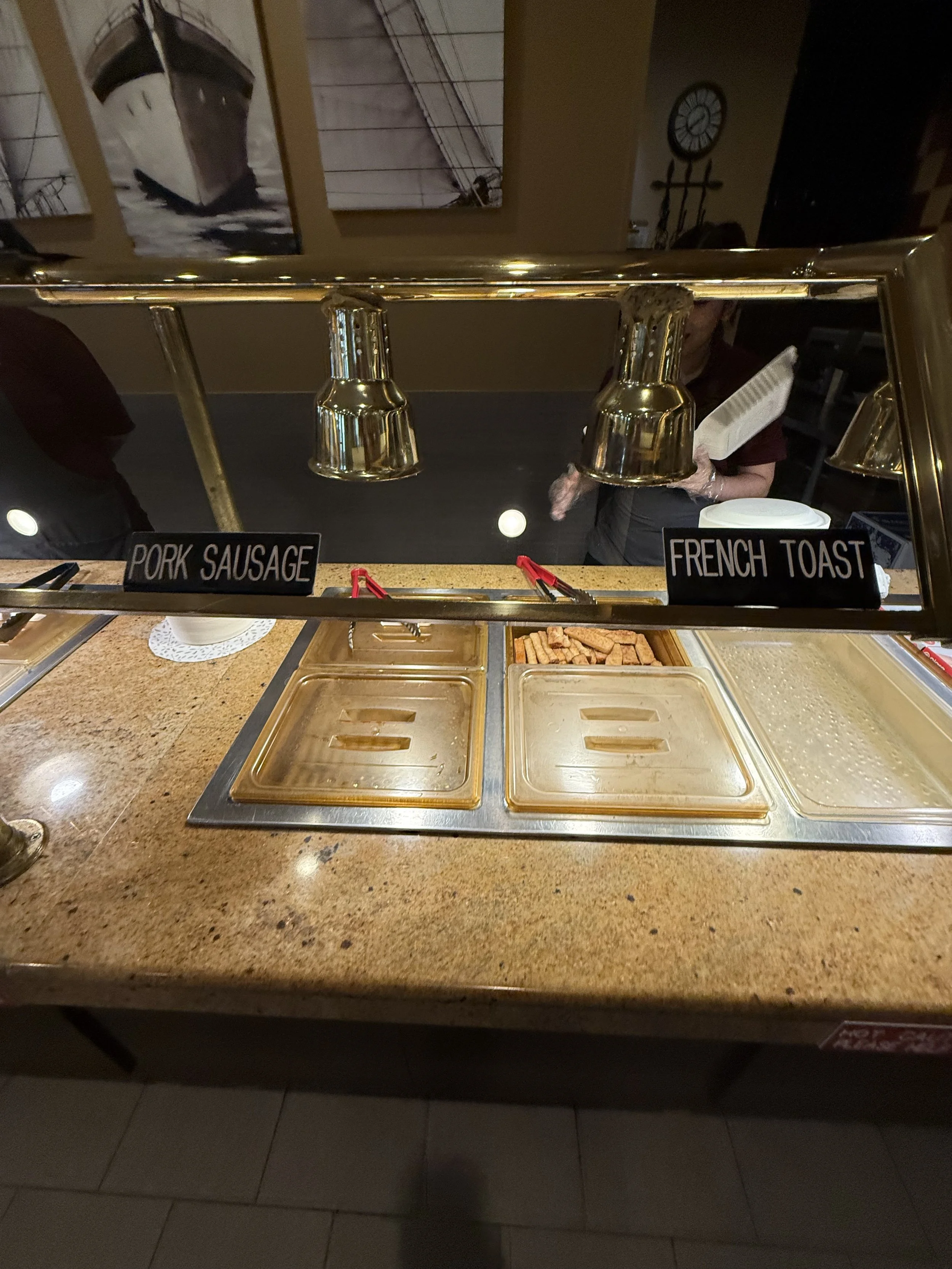 Buffet with labels for pork sausage and French toast, with food trays underneath.