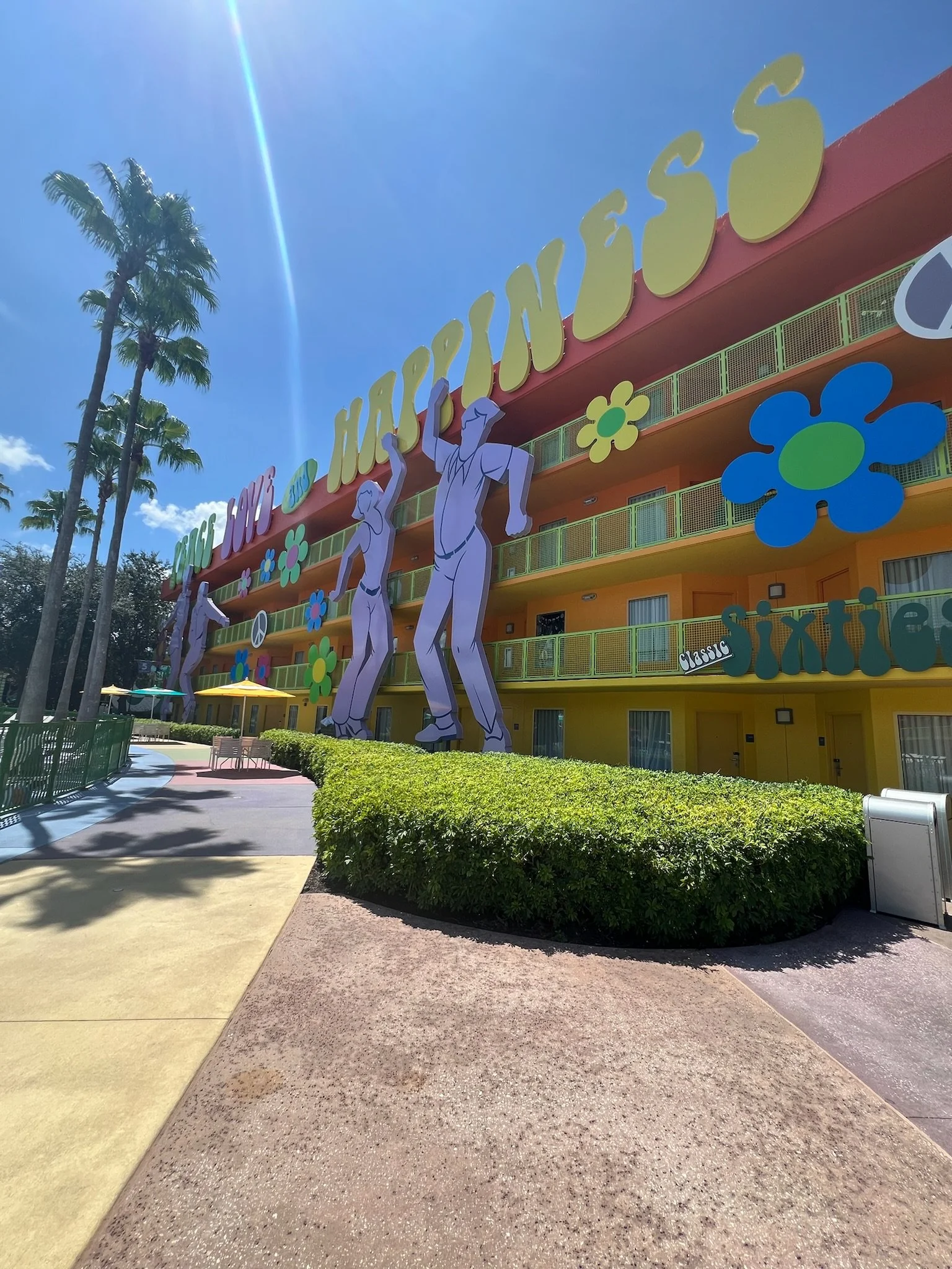 Colorful motel with large illustrated dancing figures and flowers, with the words "Love, Peace, Hope, Happiness" on the sign.