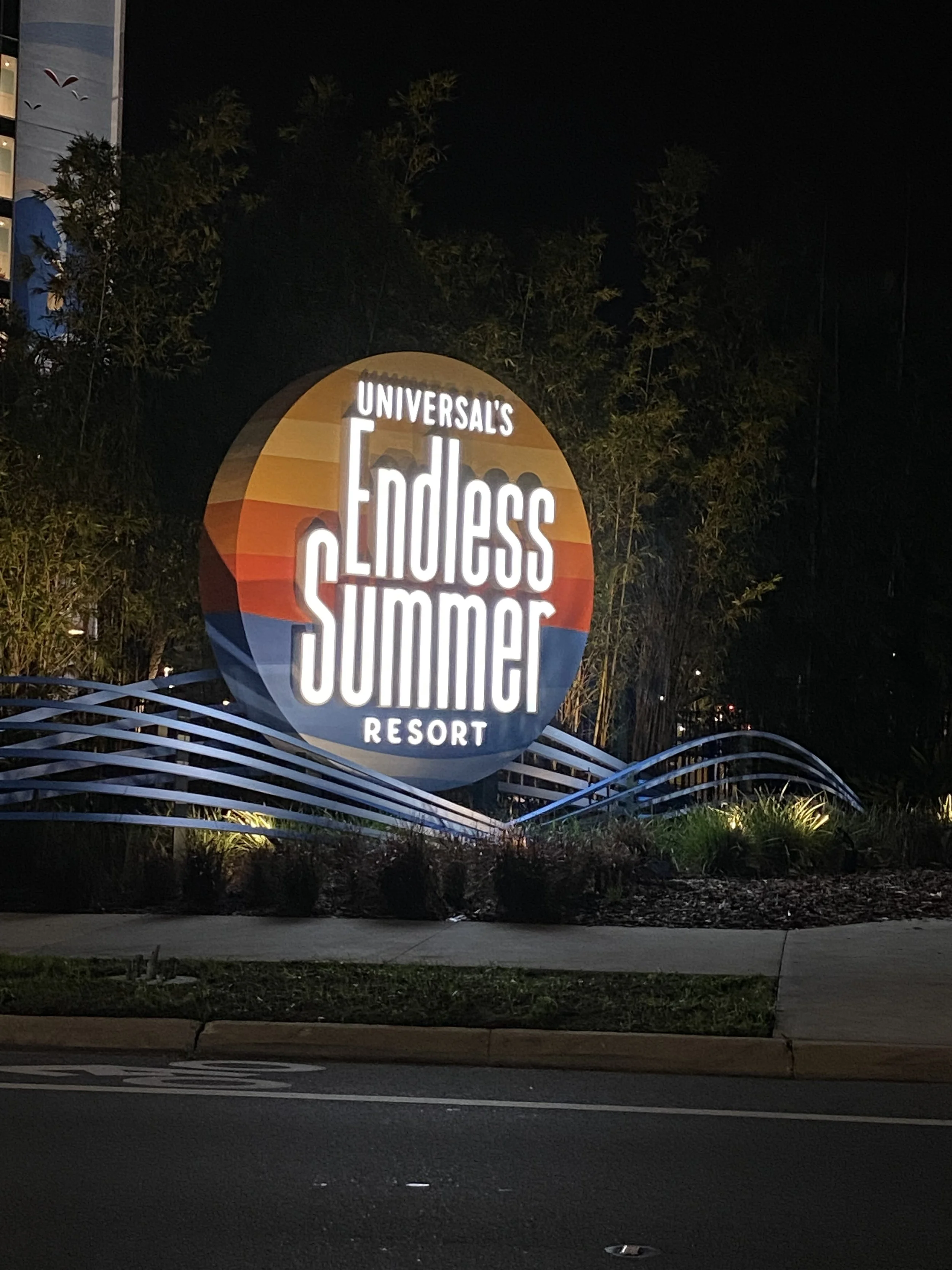 Night view of the entrance sign for Universal's Endless Summer Resort, featuring a colorful circular logo and illuminated text.