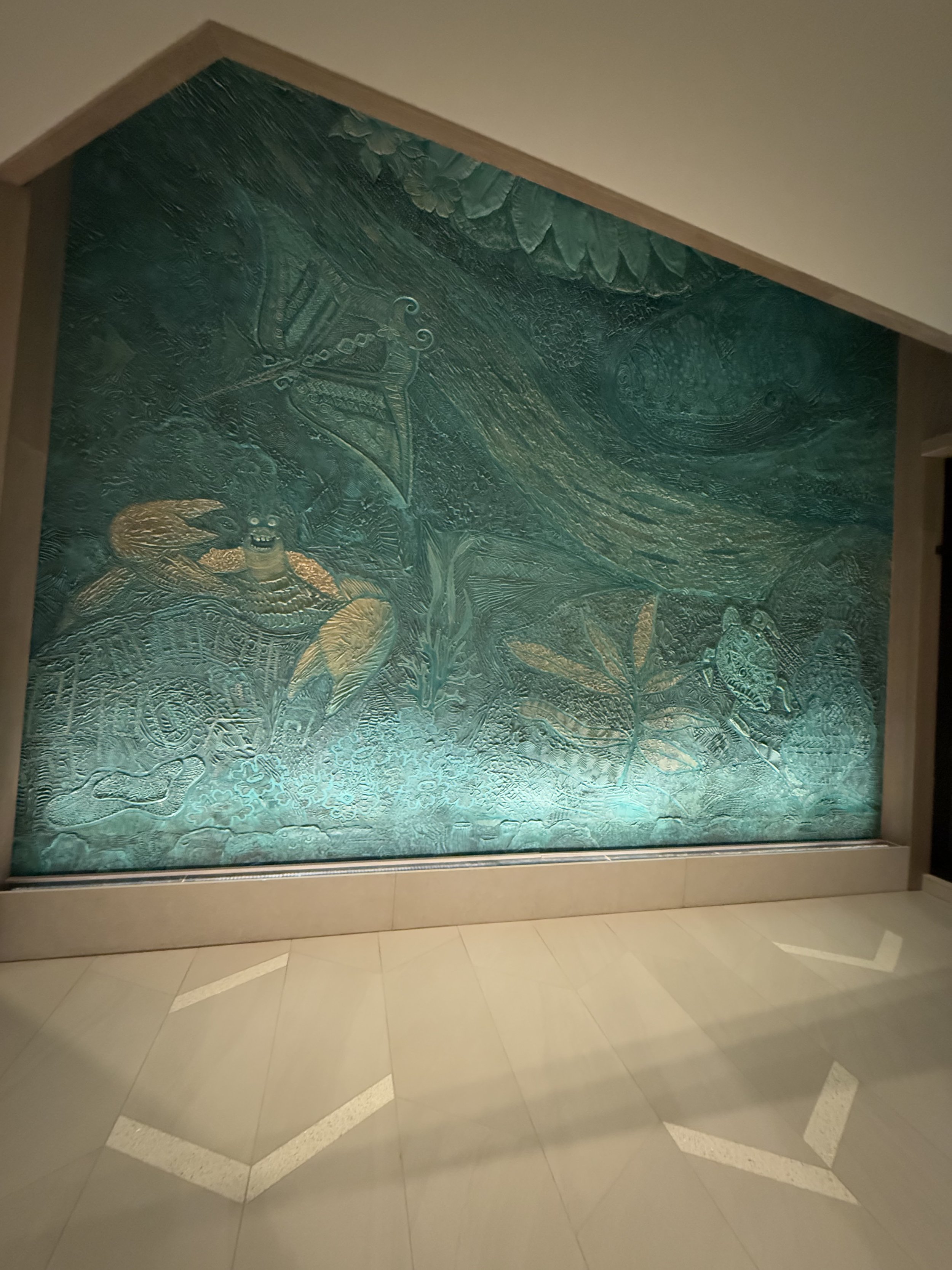 A large, illuminated wall mural with intricate marine and oceanic designs, including a crab, dragons, and large leaves.
