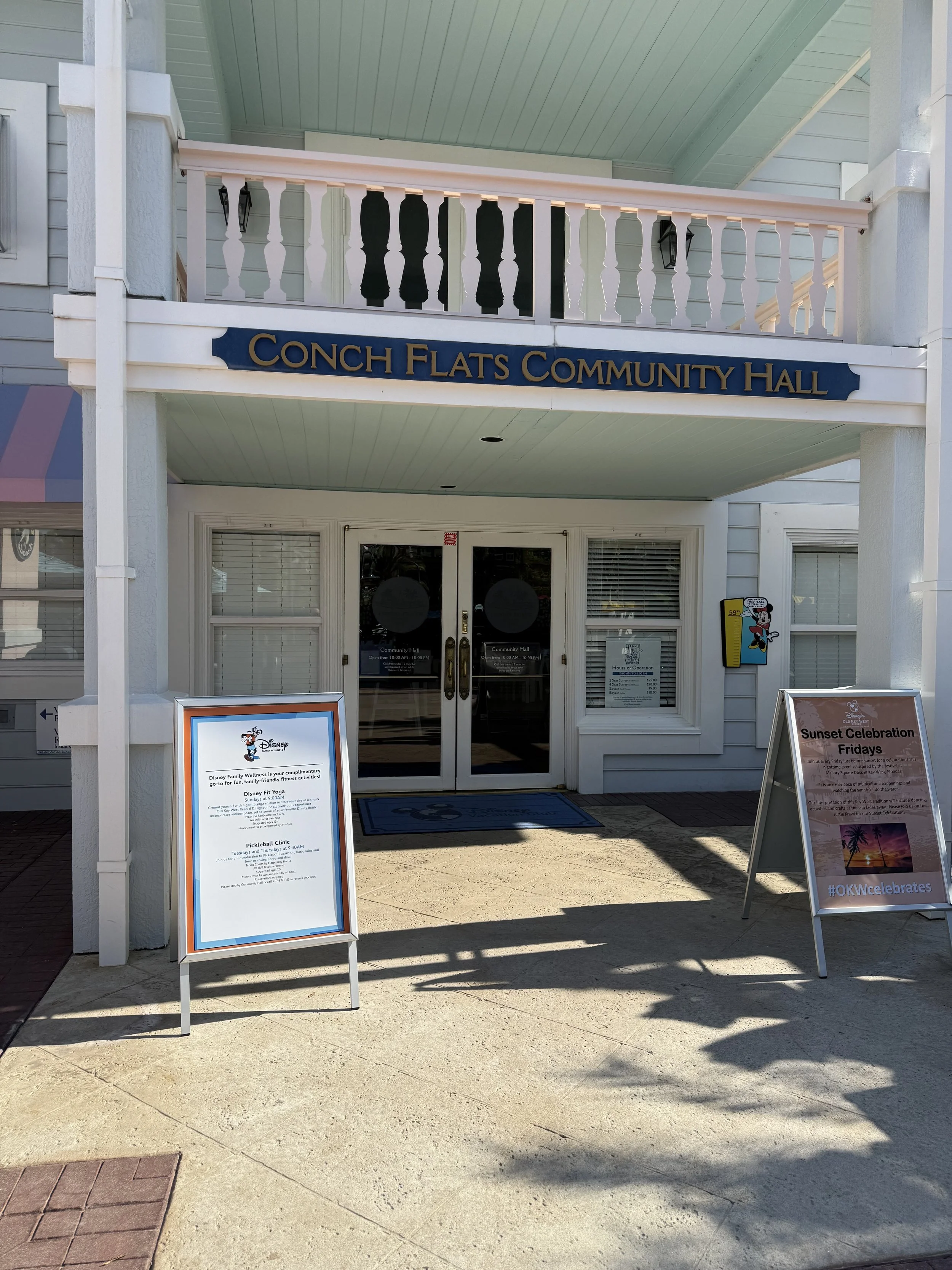 Entrance to Conch Flats Community Hall with signs promoting Disney events and sunset celebration Fridays.