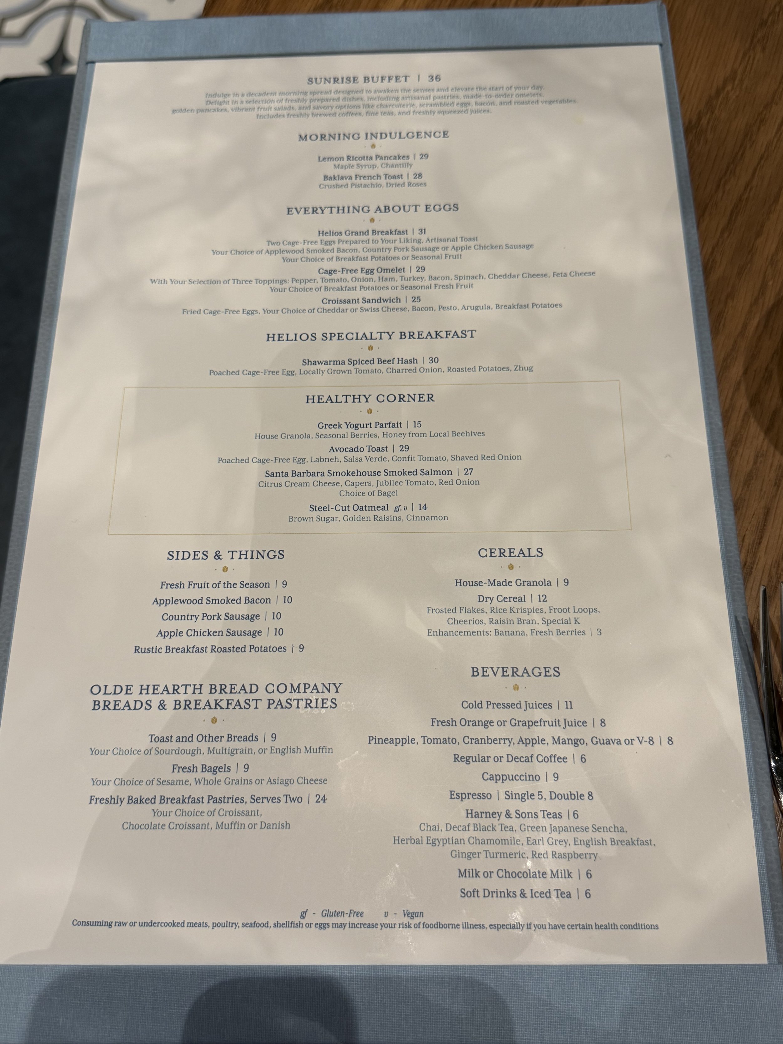 Menu featuring breakfast options such as lemon ricotta pancakes, baguette French toast, eggs, breakfast sandwiches, healthy corner with yogurt, toast, salmon, and oatmeal, sides like fresh fruit and smoked bacon, cereals, baked goods, beverages inclu