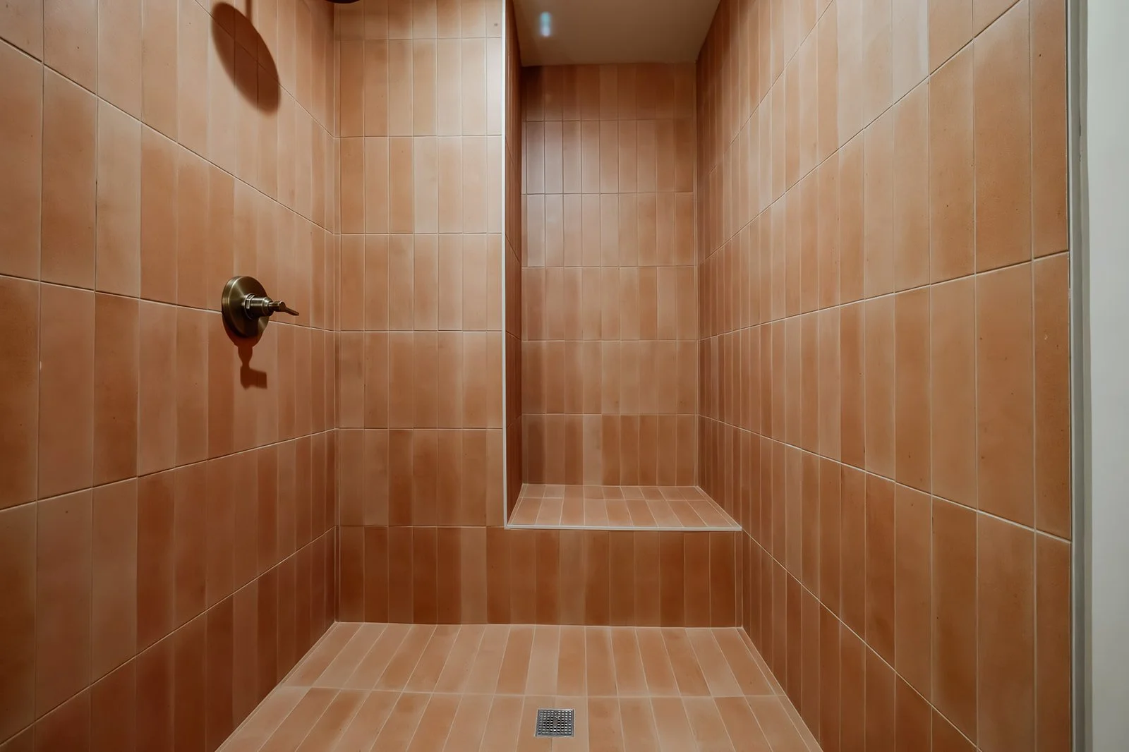 Empty shower with orange tiles and a built-in niche. No showerhead or other fixtures visible.