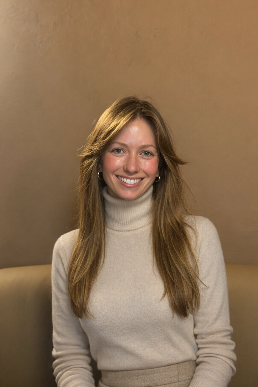 Et portrett av en smilende Marie Moxnes Harfjeld, medgründer av Crowna, iført beige turtleneck og øredobber, sittende foran en lysebrun vegg.