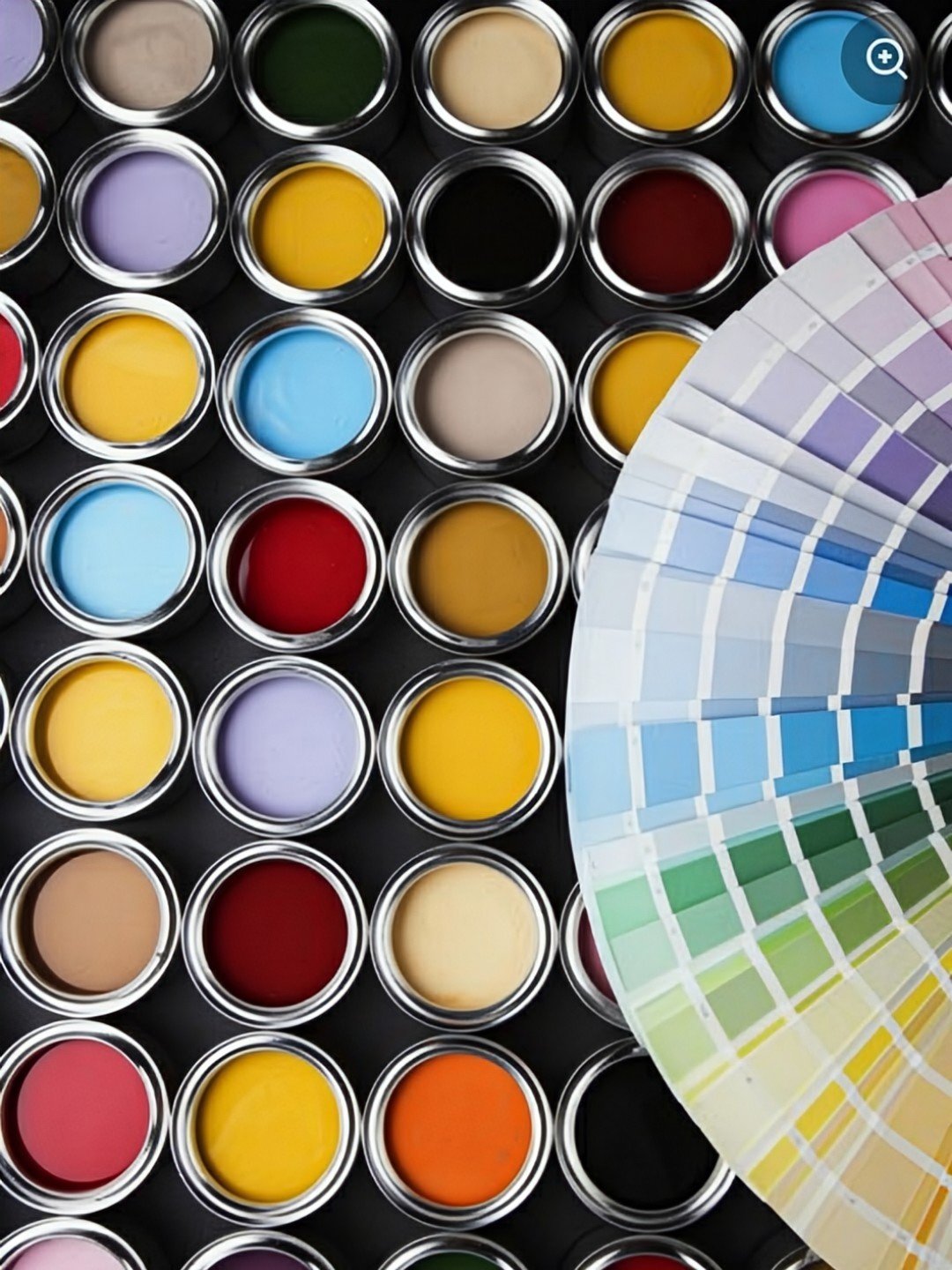 Many open cans of bright colors with a color fan open across them.