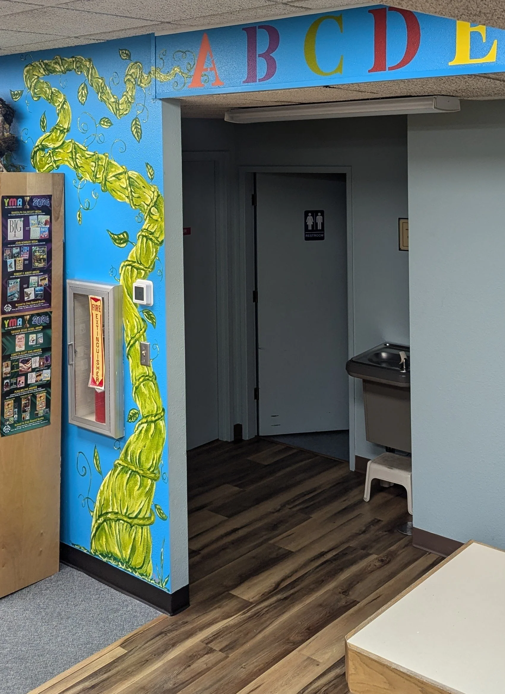 Bright blue wall with green bean stalk painted on it