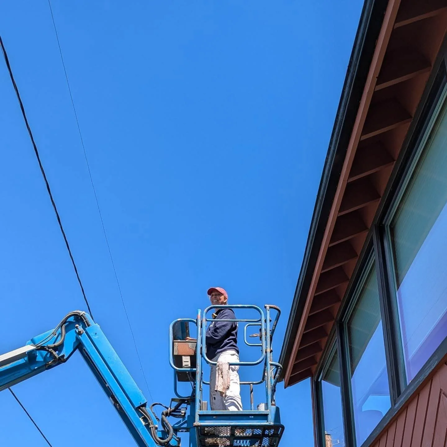 Julie Chapman up on a boom lift in front of building