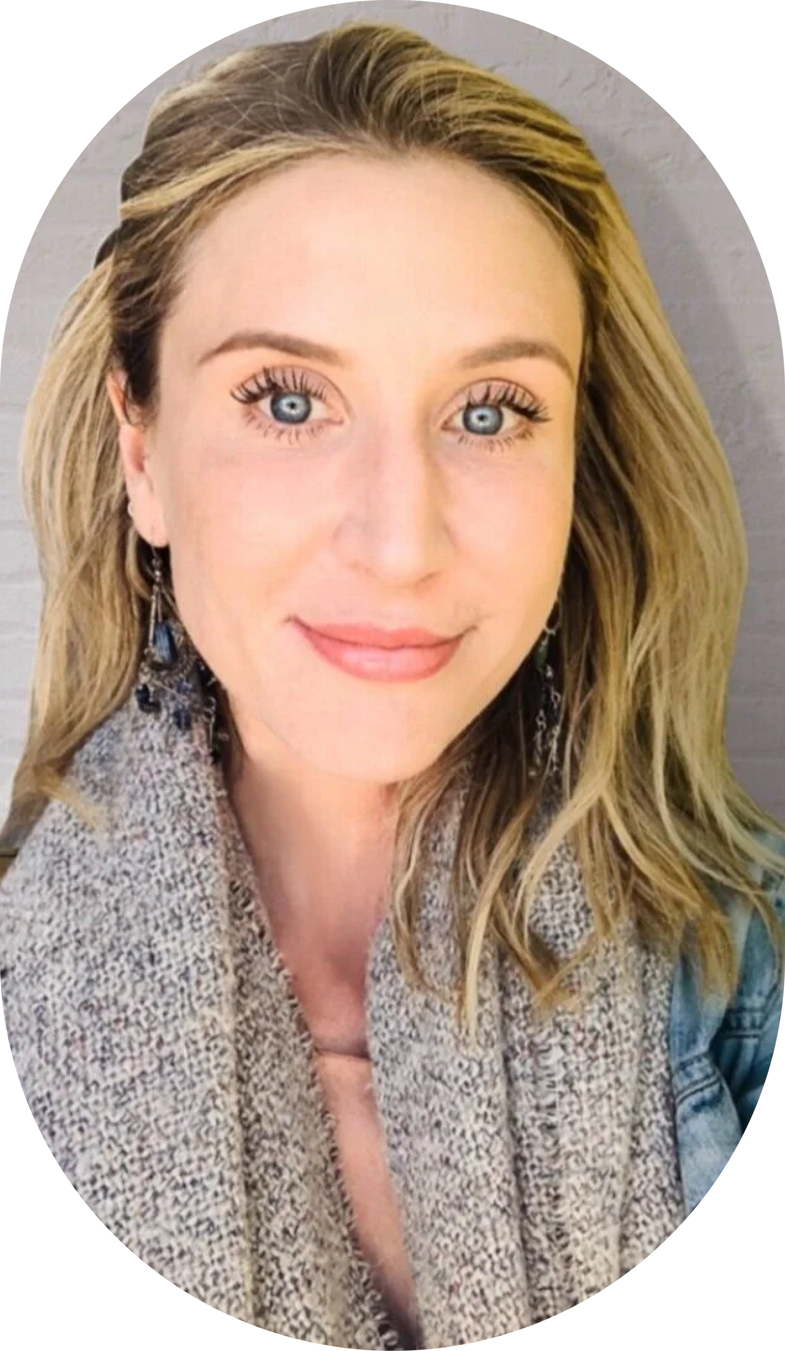 A close-up portrait of Dr. Jennifer Huggins with blonde hair, blue eyes, and a gentle smile, wearing earrings and a light-colored, textured top.