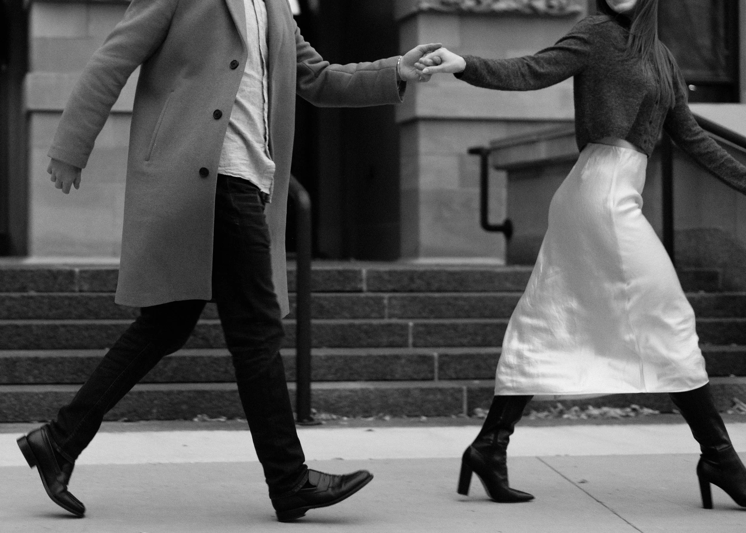People walking down stairs outside, holding hands, in a black and white photo.