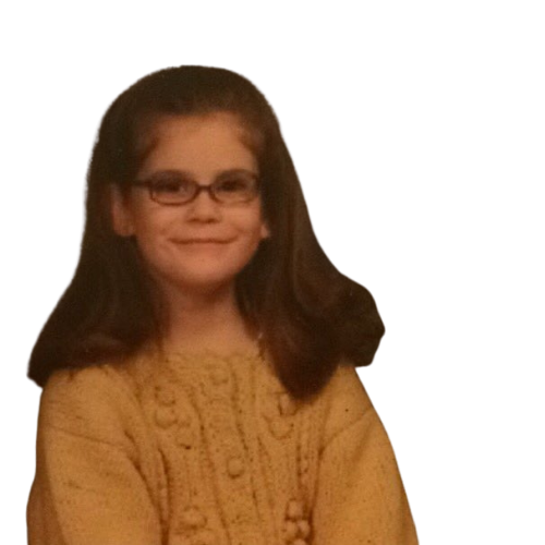 A young girl with glasses and long brown hair, wearing a yellow sweater, smiling.