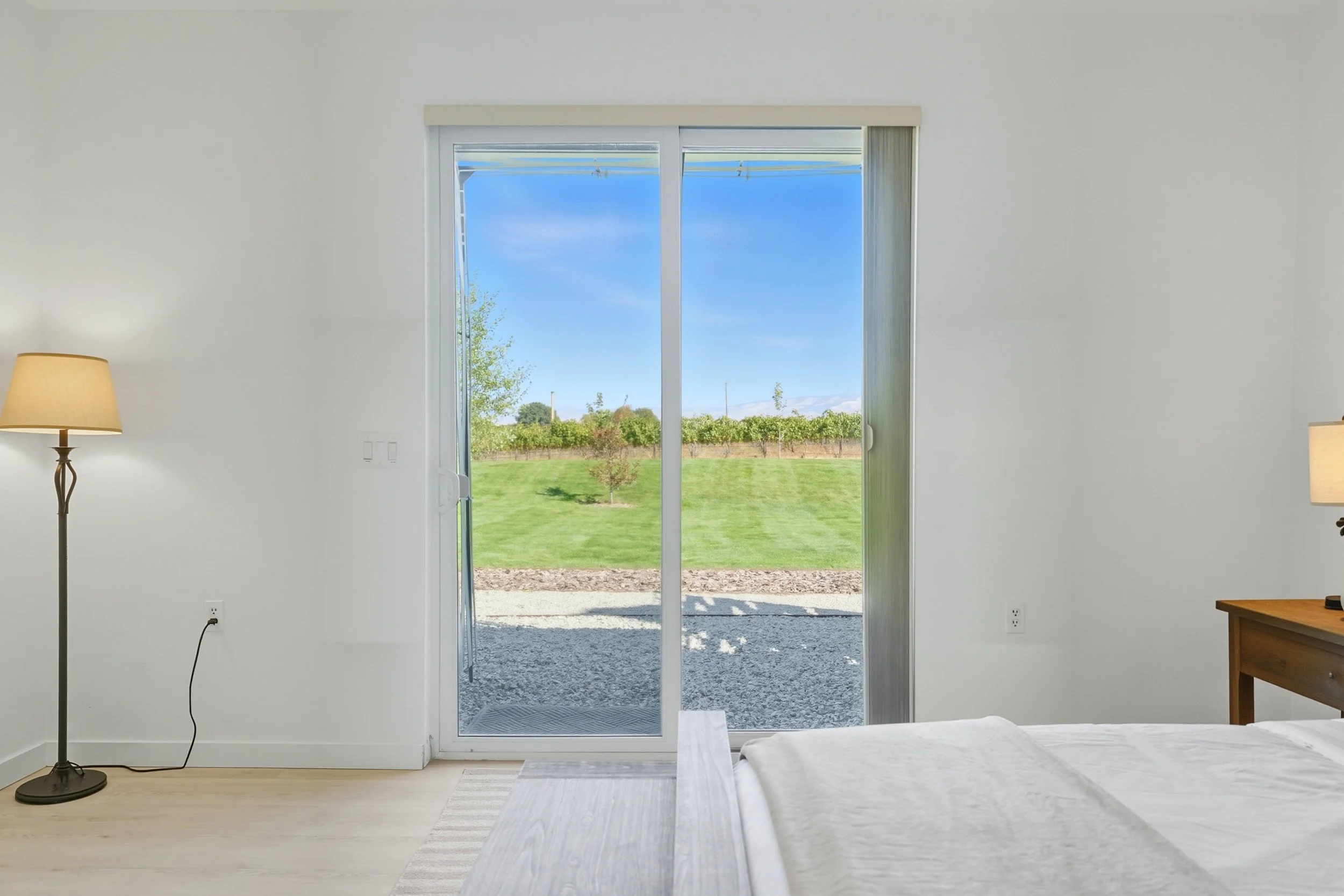View through sliding glass door to a grassy outdoor area with trees and a clear blue sky.