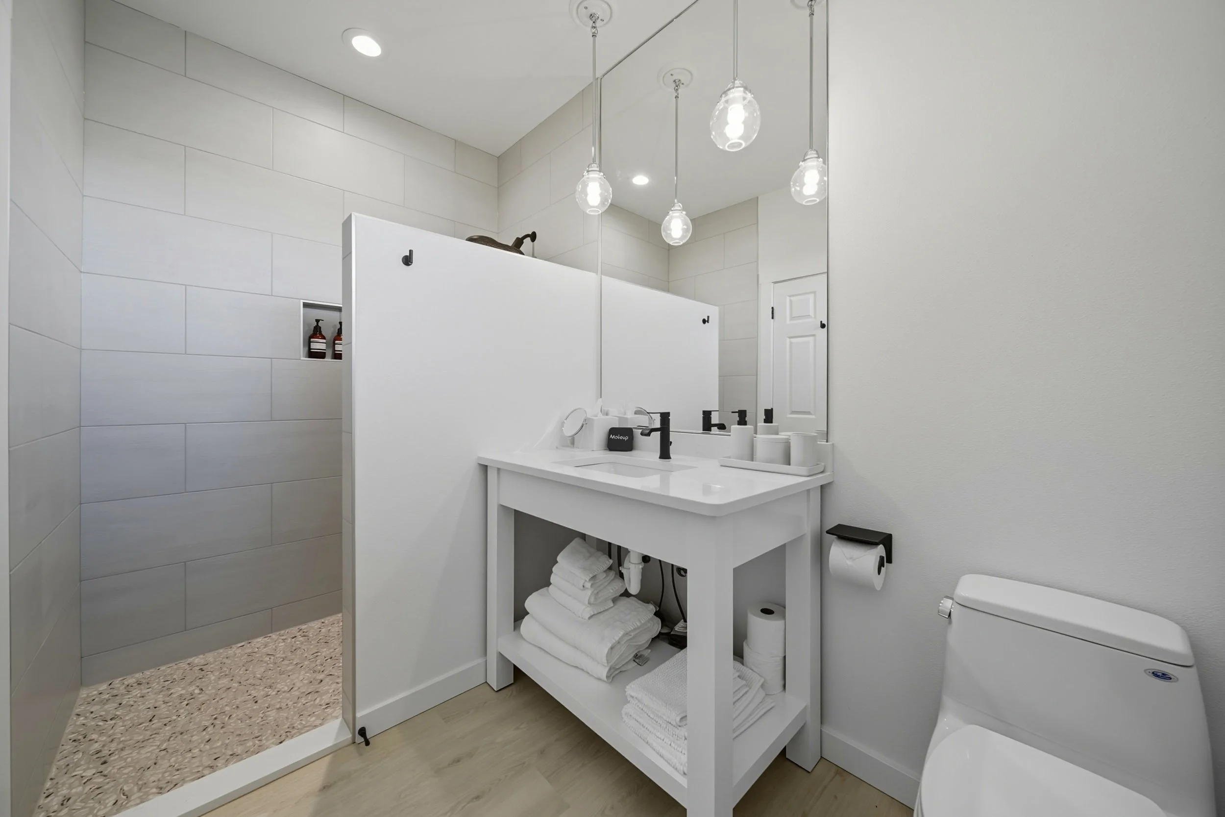 Modern white bathroom with a vanity, towels, and a toilet.