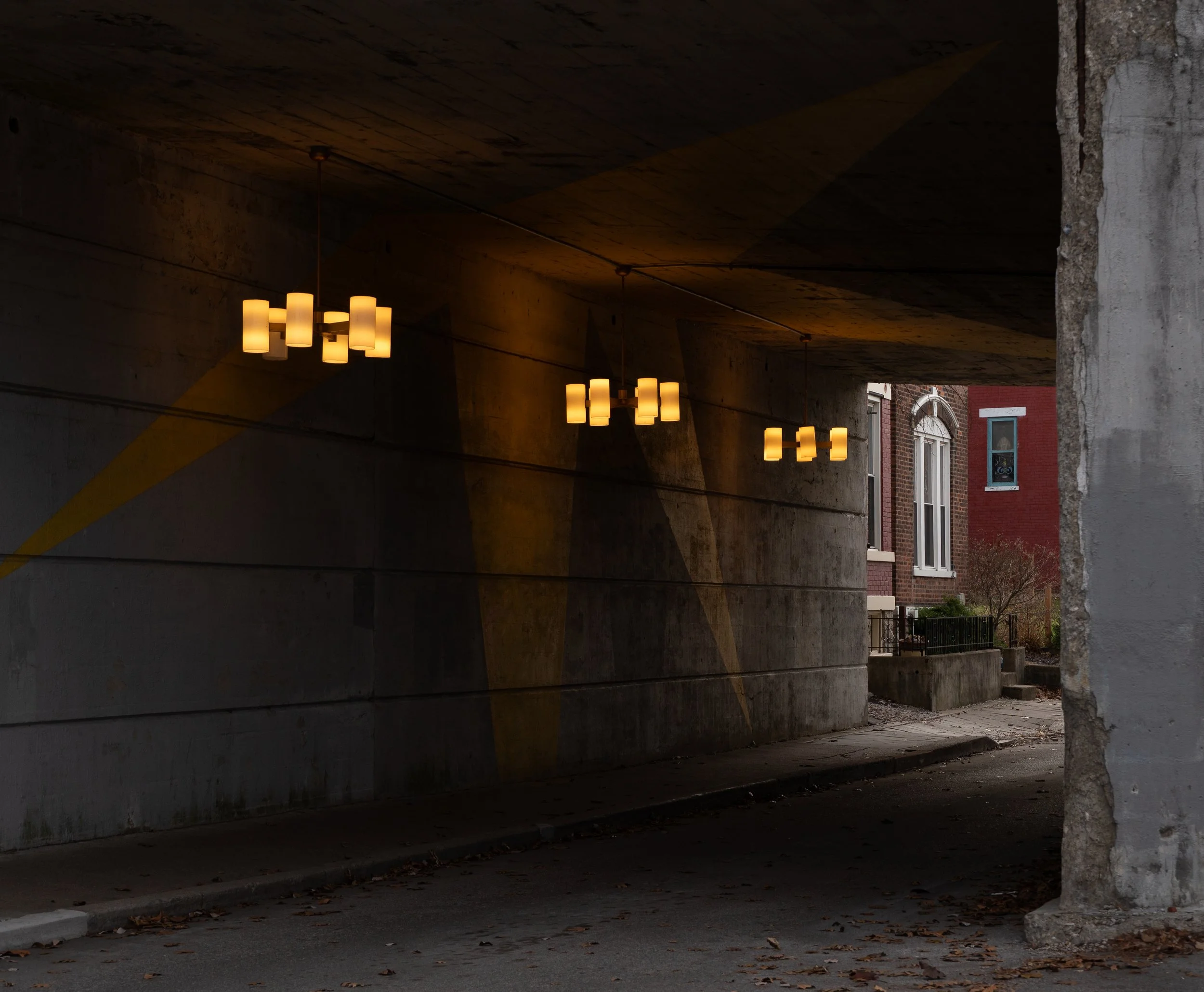 Underpass with hanging yellow lights and residential buildings in the background