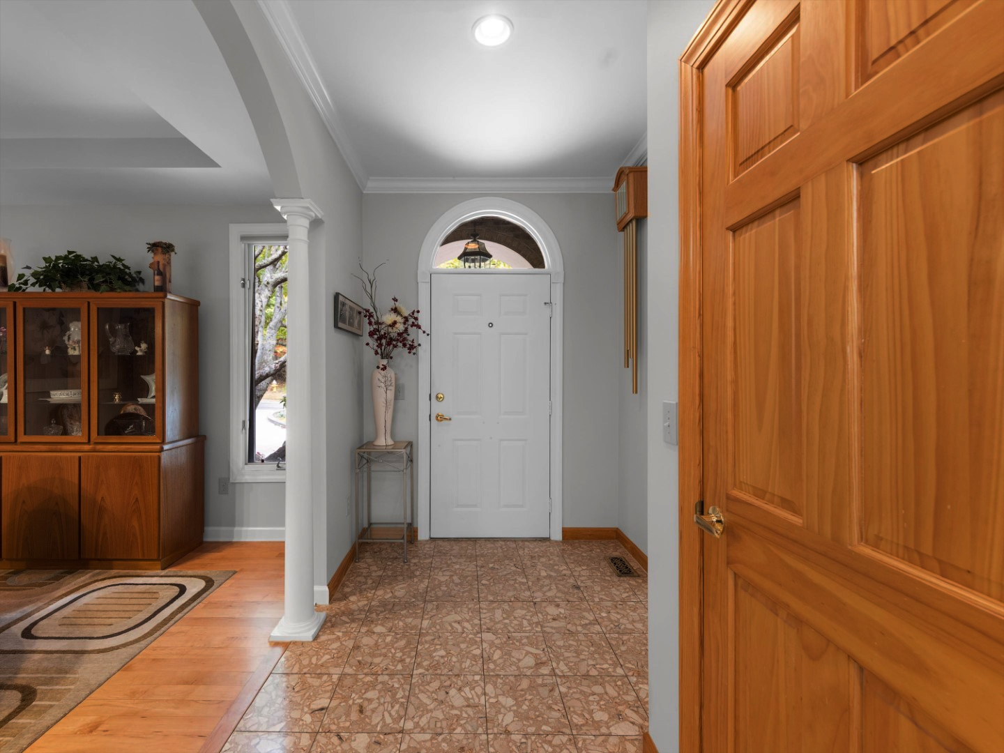 Carriage park entry way before remodel with pink marble and blonde wood floors and blonde interior door color