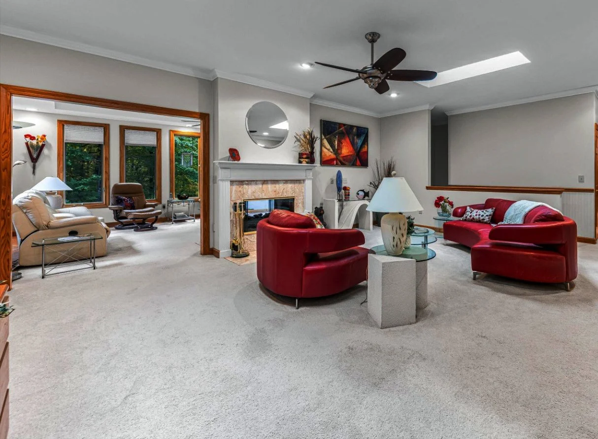 Carriage park living room before remodel with white carpet and blonde wood trim and extra wall enclosing fireplace