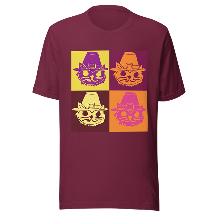 Maroon T-shirt with a 2x2 grid of stylized cat faces wearing pilgrim hats in yellow, orange, cream, and pink colors.
