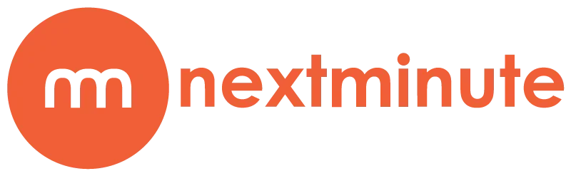 Modern wooden house with large glass window set against mountain landscape, surrounded by green plants and shrubs.