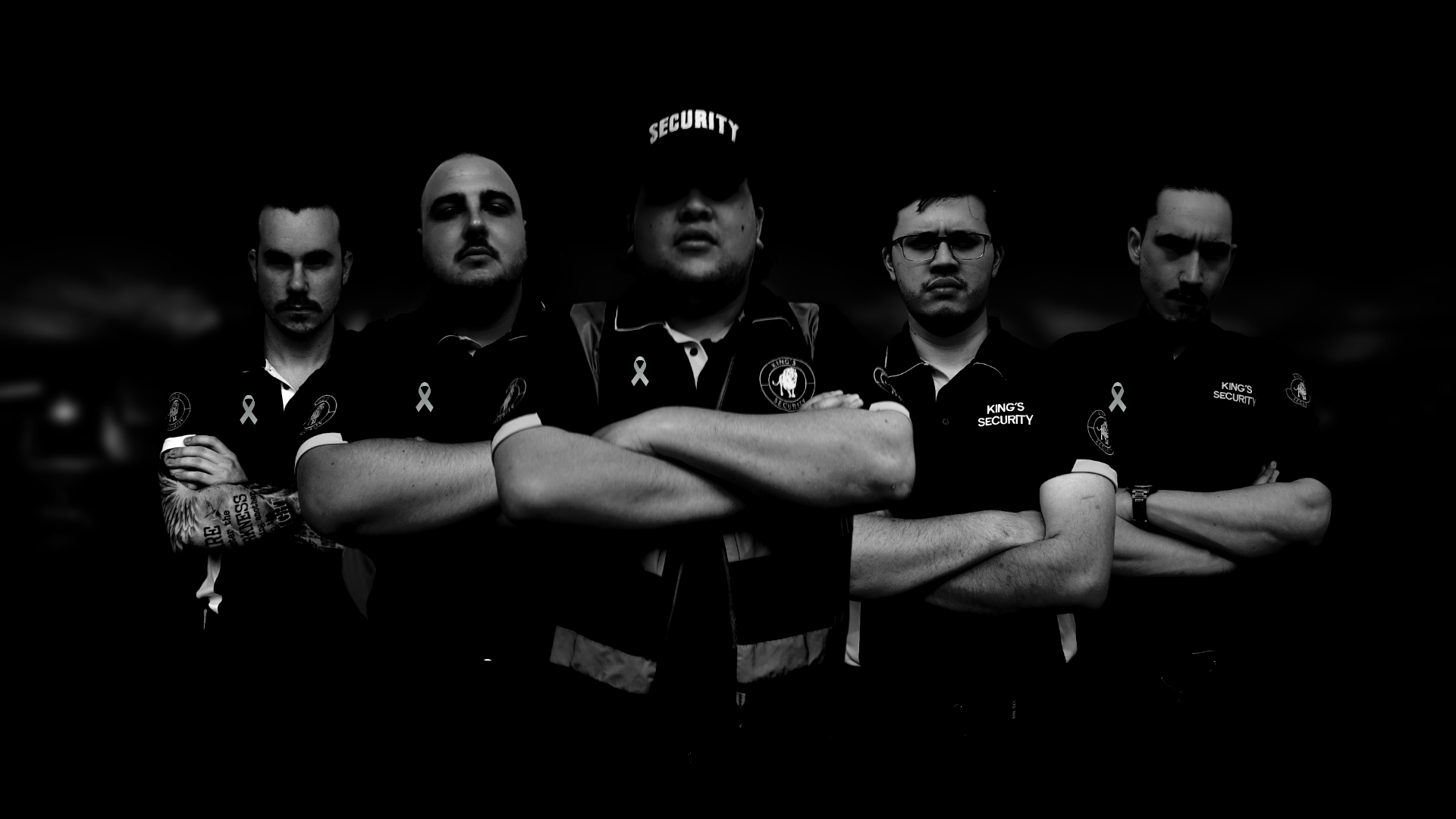 A group of five security personnel standing with arms crossed, dressed in black uniforms with 'KING'S SECURITY' patches and white ribbons, standing against a dark background.