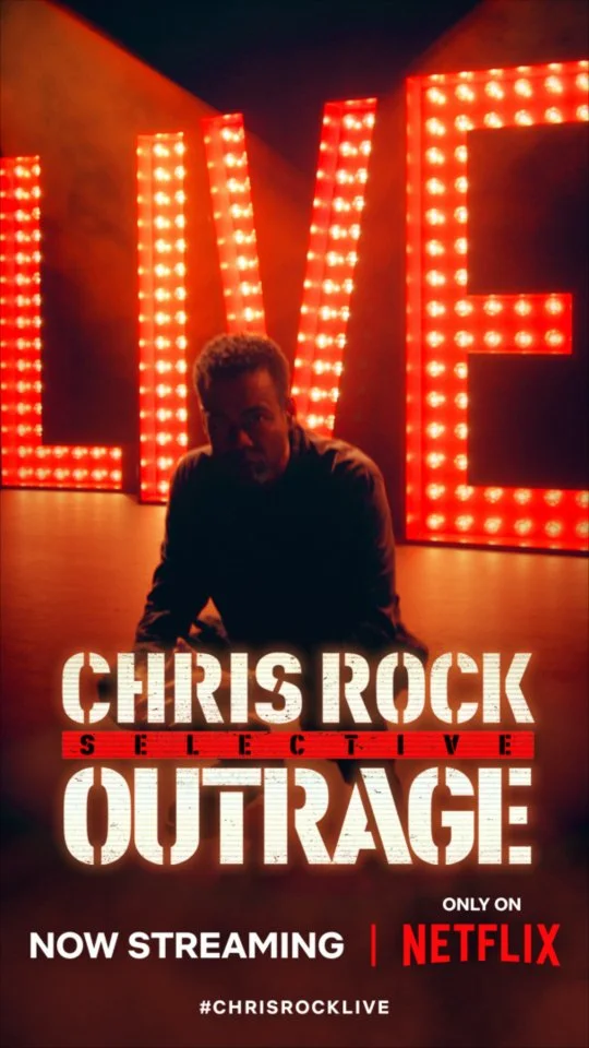 A promotional poster for the Netflix comedy special 'Chris Rock: Selective Outrage.' Features a person sitting in front of large illuminated red letters spelling 'LOVE,' with the title and streaming information displayed at the bottom.