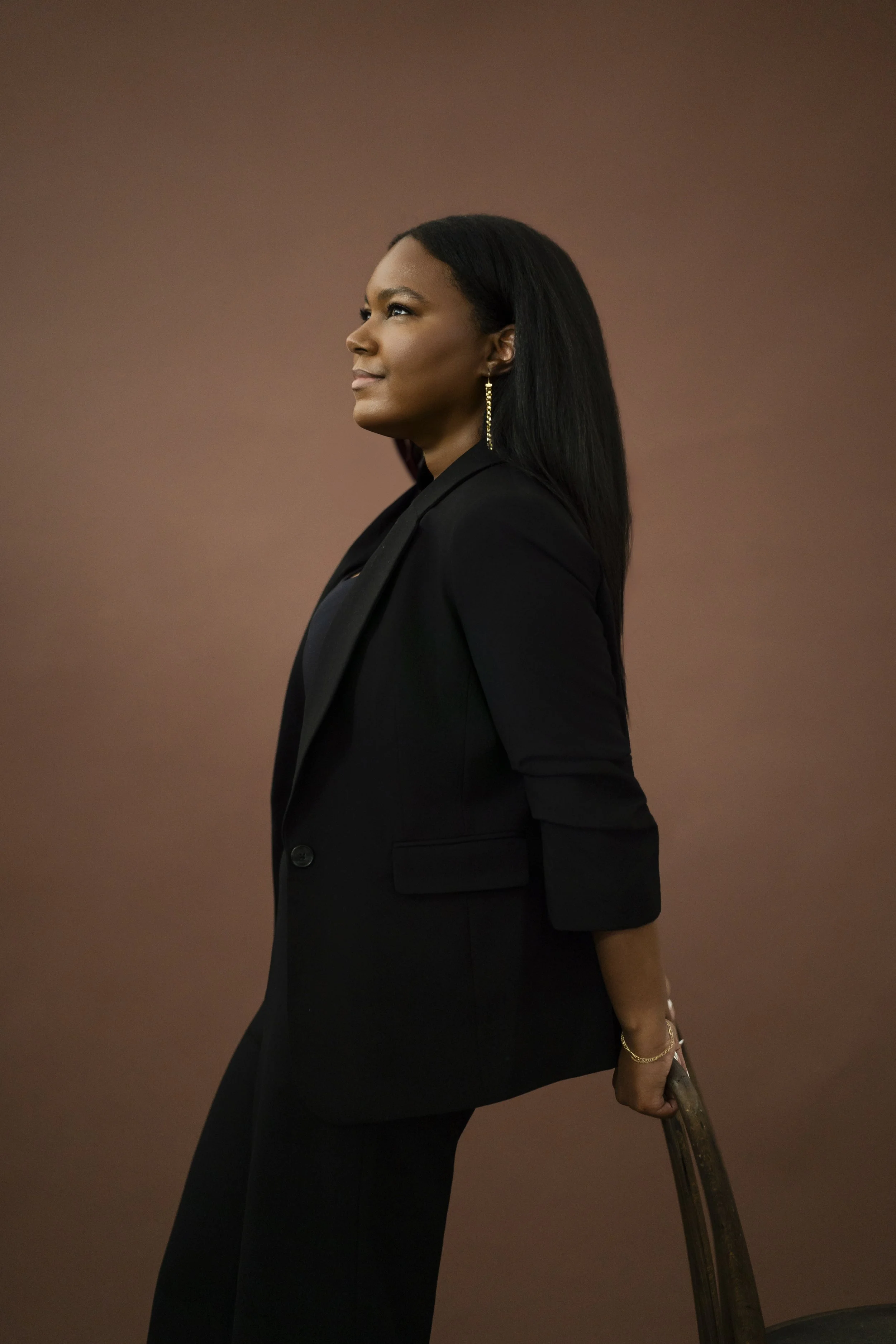 Ciera Logan in a black blazer with a confident expression, standing against a plain brown background.