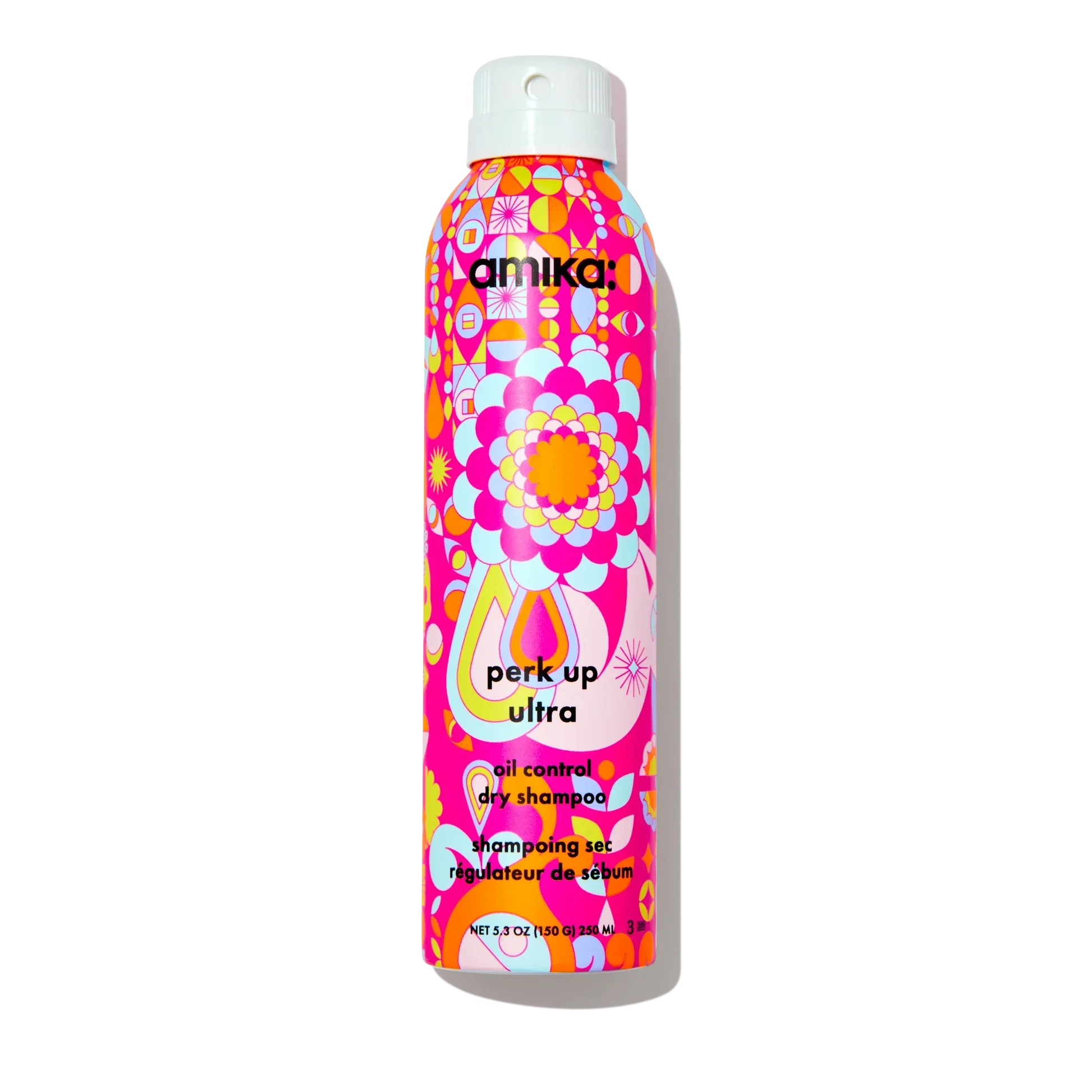 Three bottles of Amika perk up plus extended clean dry shampoo for extending hair freshness, with a colorful pink, orange, and purple floral pattern on the bottles, placed next to a coin for scale.