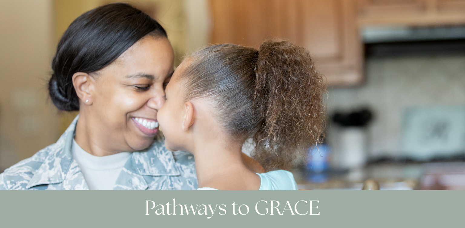 A woman in military uniform smiling and touching noses with a young girl with curly hair in a kitchen.