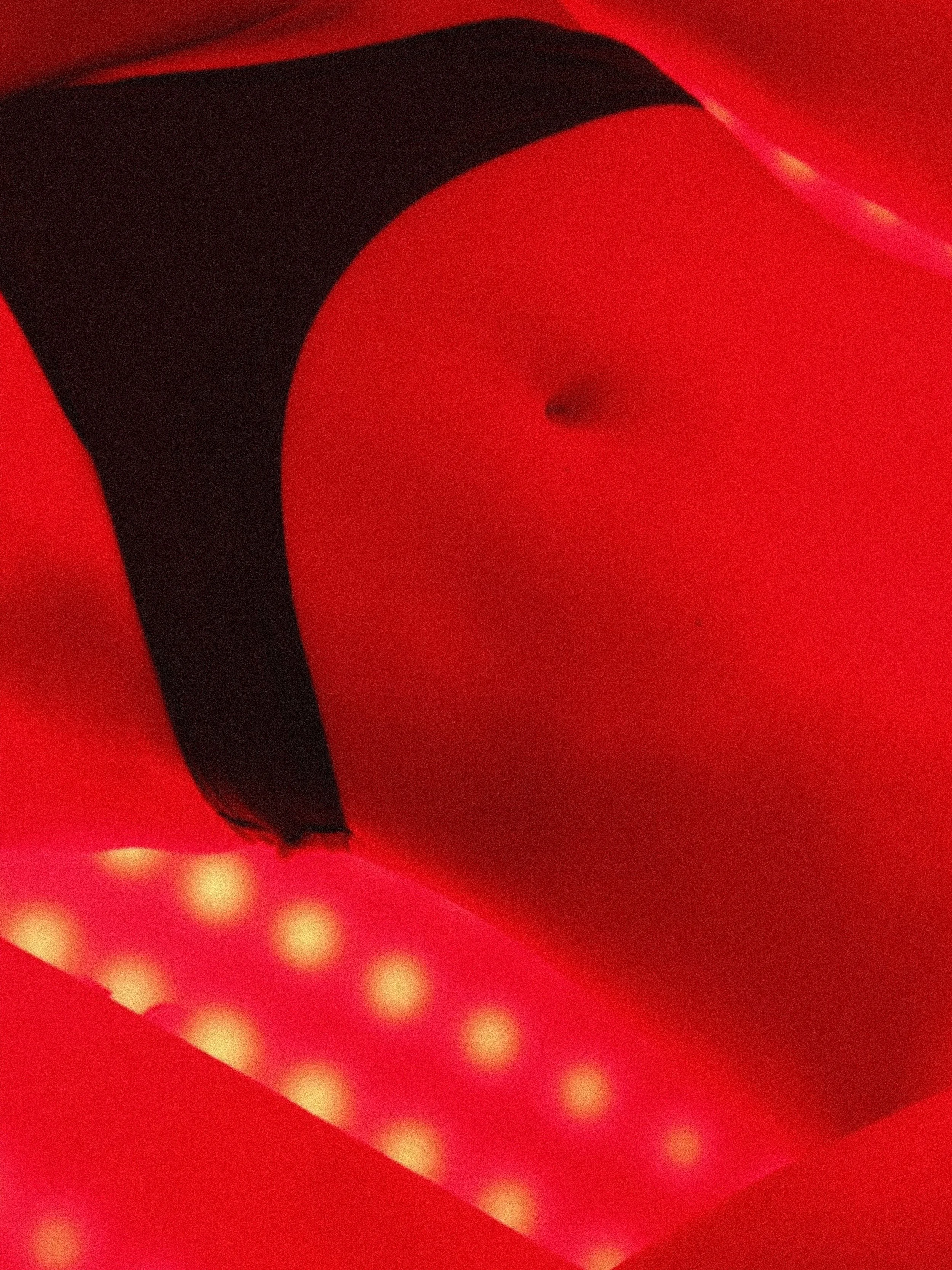 Close-up of a person in black underwear, highlighting a slightly protruding navel, with illuminated dots in the background.