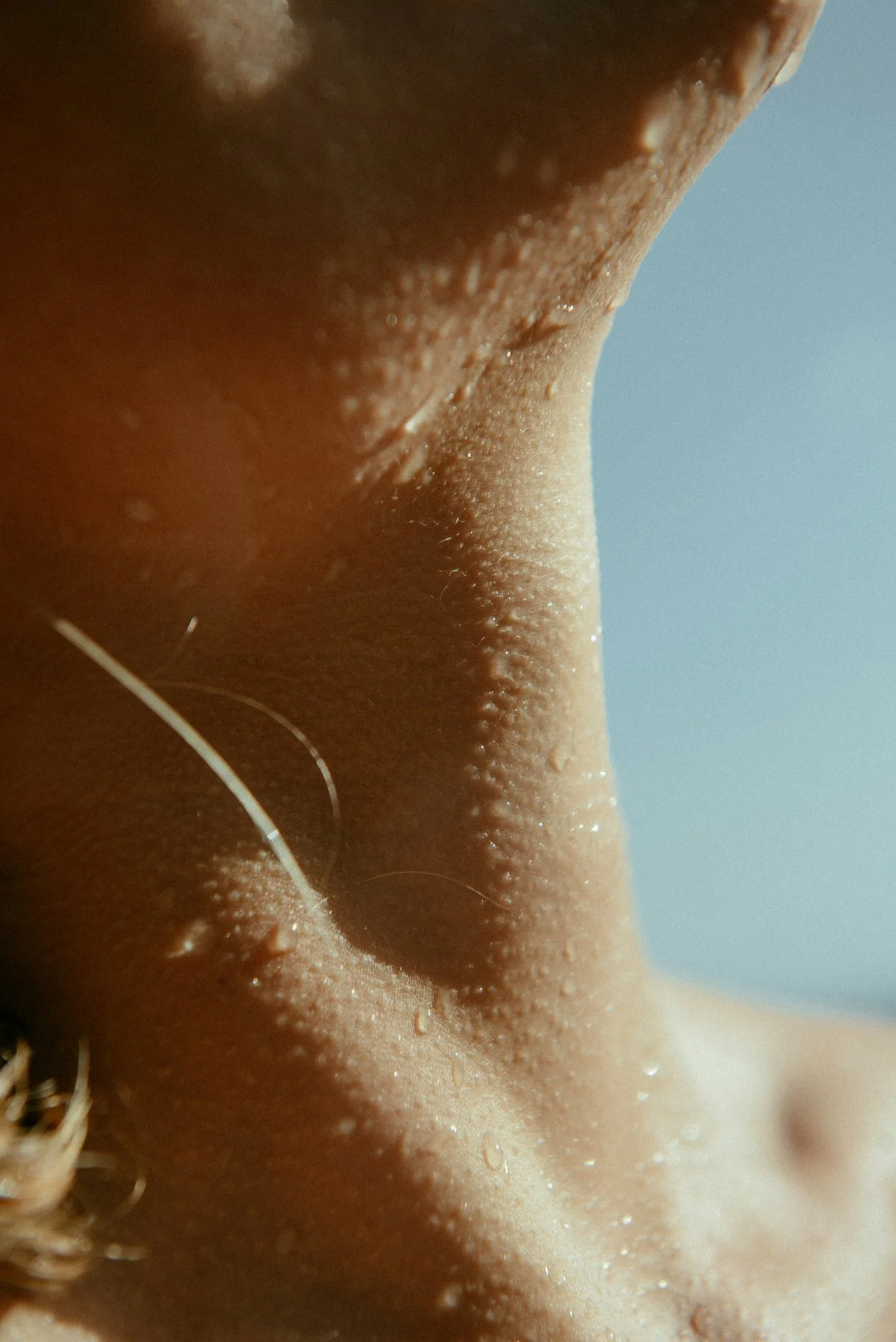 Close-up of a person's lips, fingers near face, and hand making a heart shape on their chest.