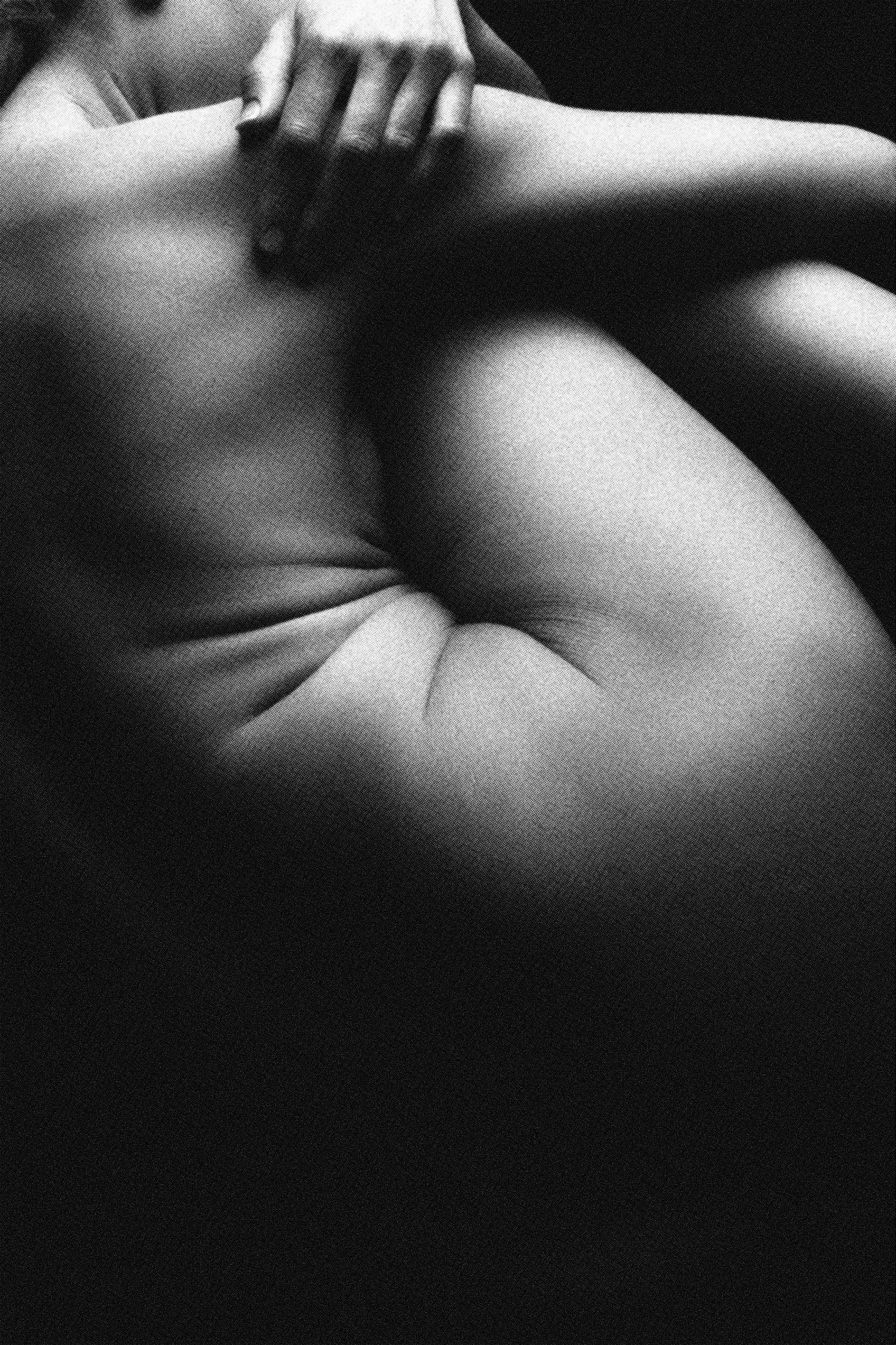 A black and white photo of a person's arm being gently touched on the shoulder by another person's hand.