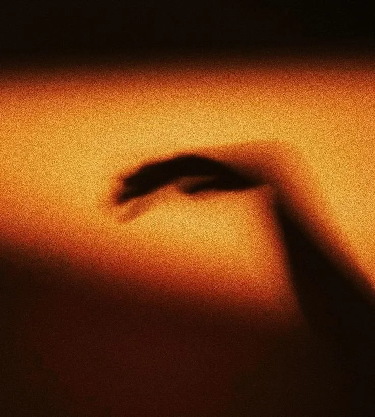 Close-up of a person's hand gently holding a small object against a warm-toned background.