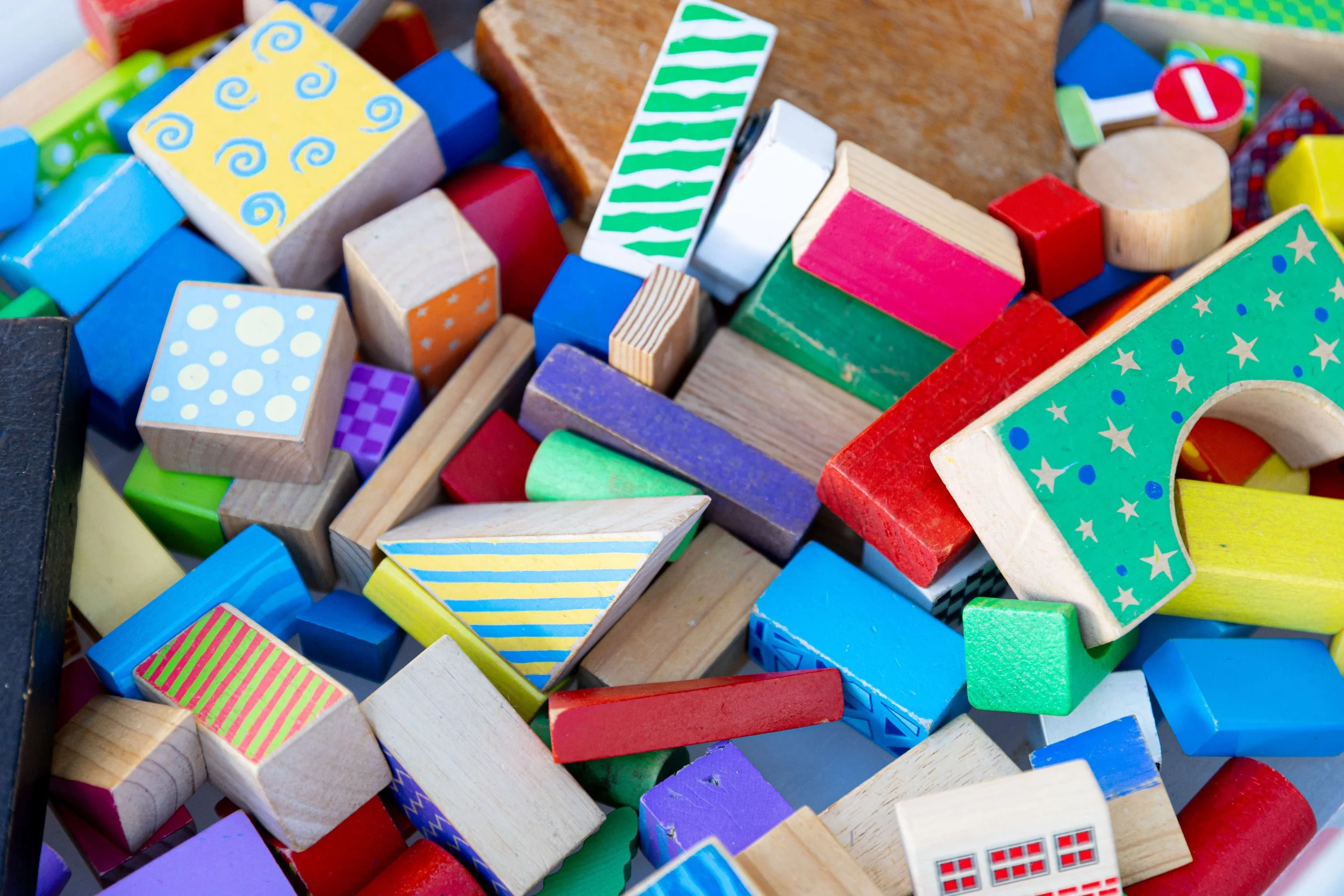 A collection of colorful wooden toy building blocks with various shapes and patterns.
