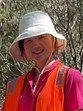 Young girl wearing a bucket hat and orange vest, smiling outdoors.