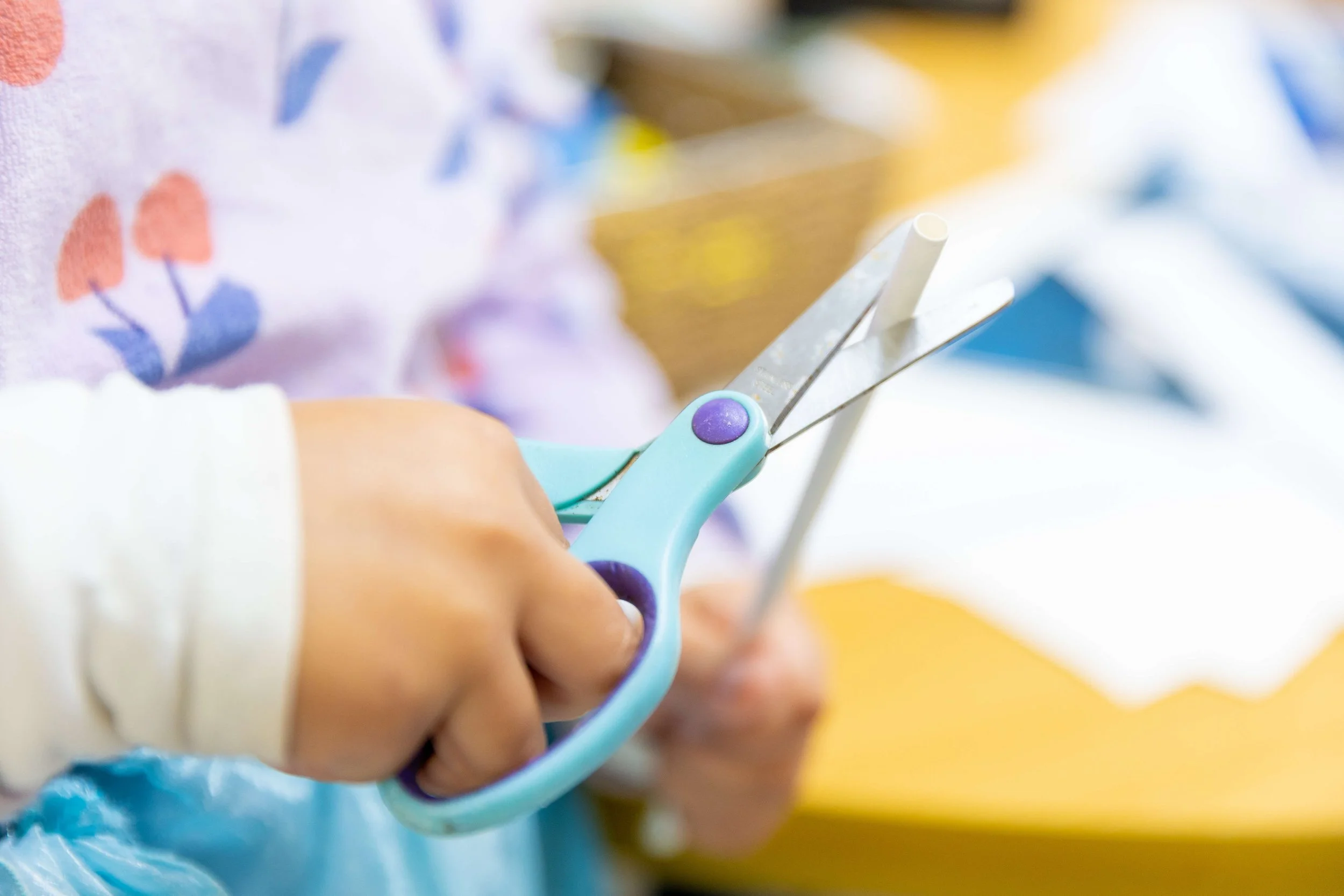 A child's hands holding scissors, cutting paper.