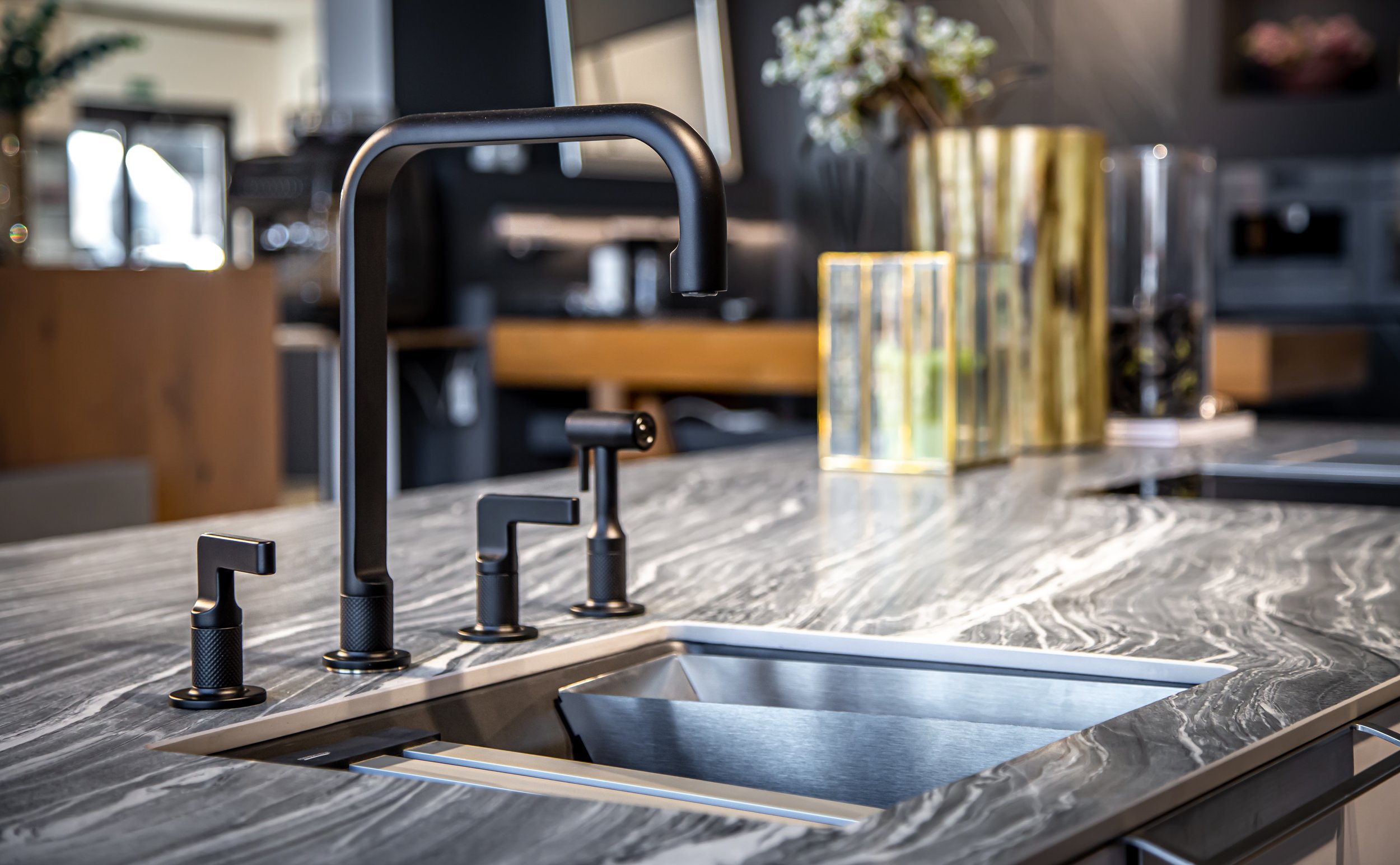 Modern kitchen sink with black faucet on a marble countertop, in a stylish kitchen.