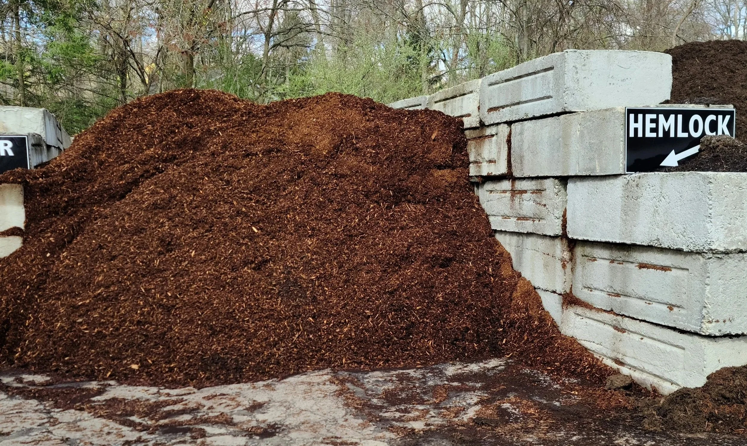 A pile of soil next to white concrete blocks, with a black sign labeled 'HELOCK' and a black arrow pointing to the left.