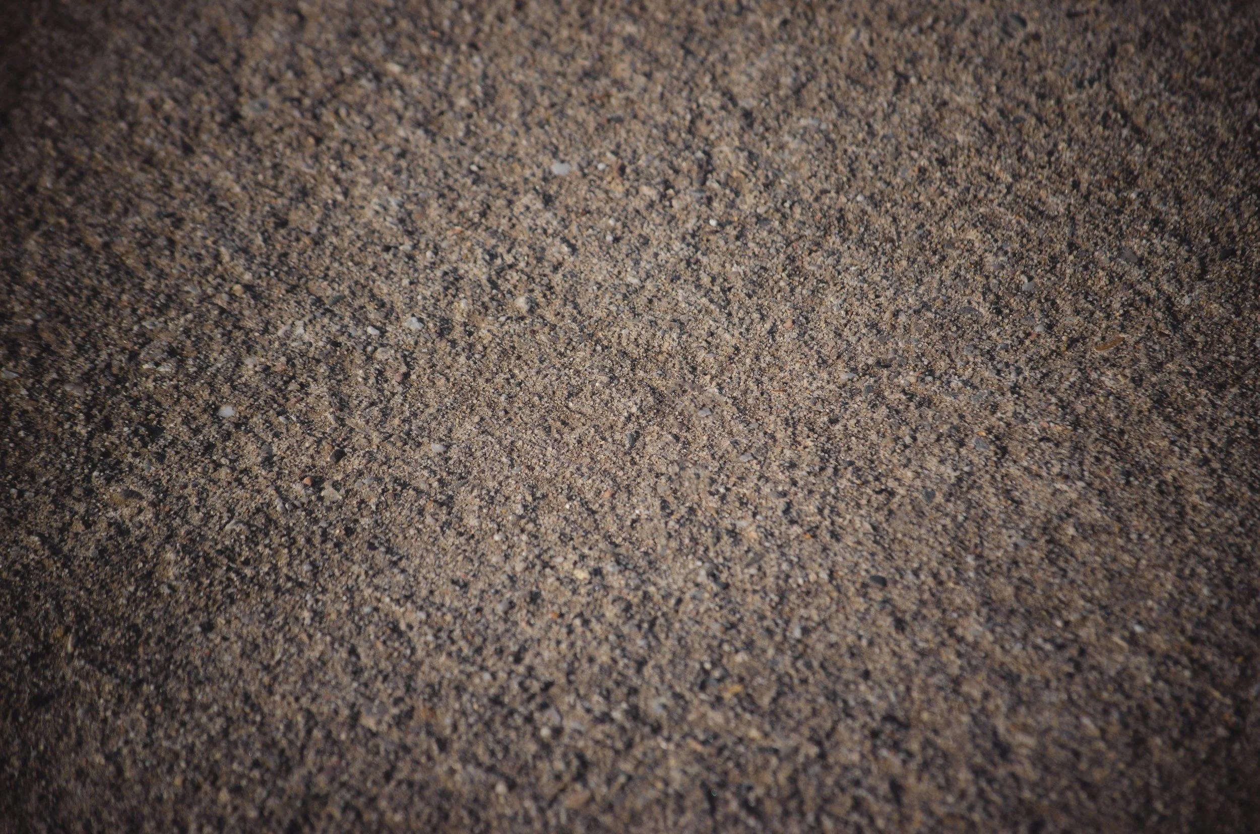 Close-up of brown sand with small pebbles.