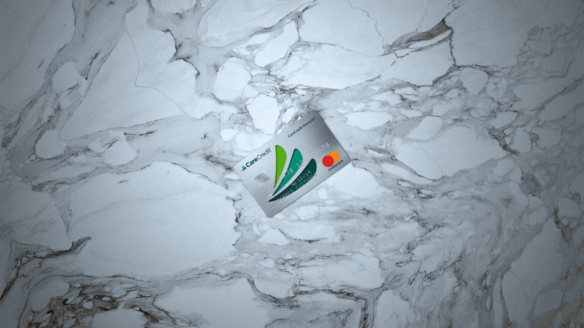 A CareCredit Mastercard credit card lying on a white marble surface.