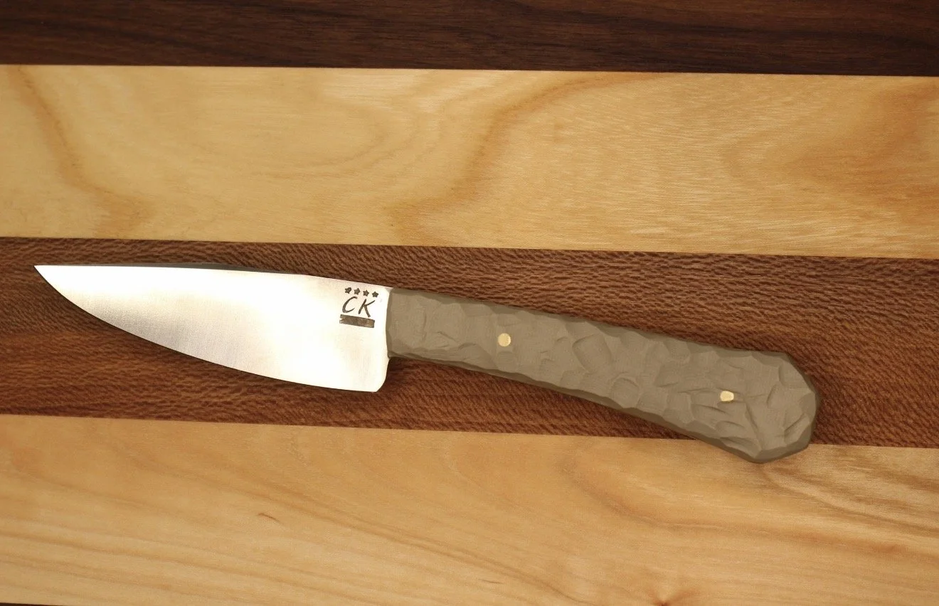 A handmade knife with a G10 textured stone-colored handle
