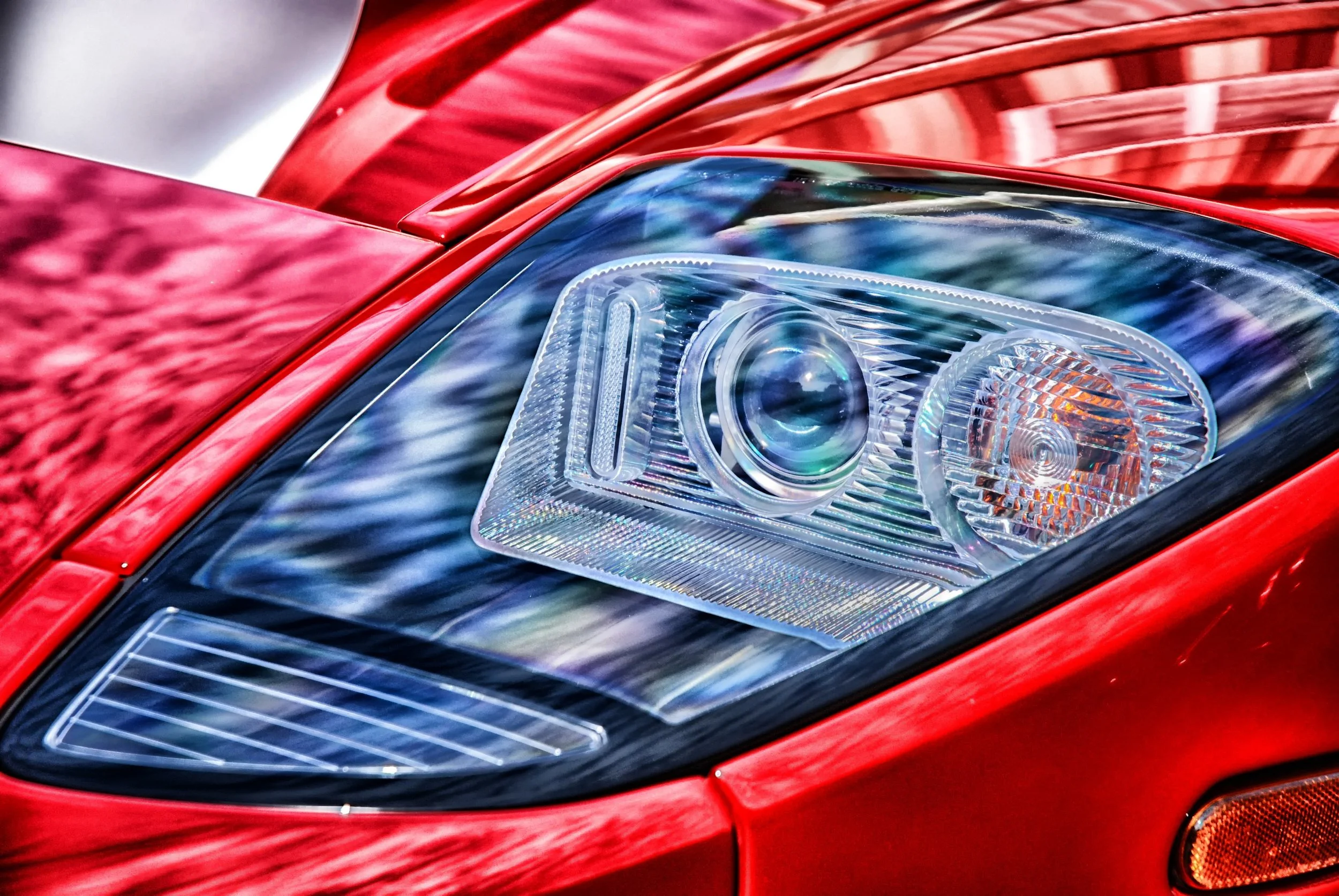 Focale sur le phare d'une voiture rouge moderne, avec des détails précis du cristallin et de la carrosserie