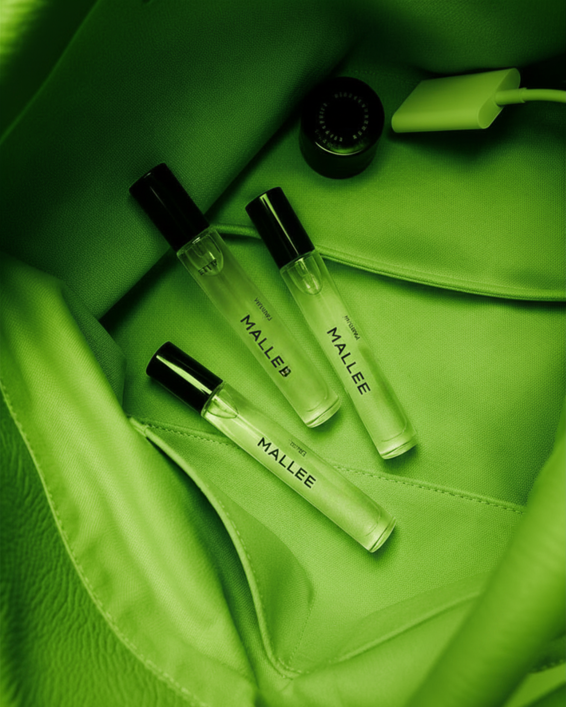 Green bag containing three clear bottles labeled 'MALLEE' with black caps, a small black vape device, and a yellow charger or electronic device.