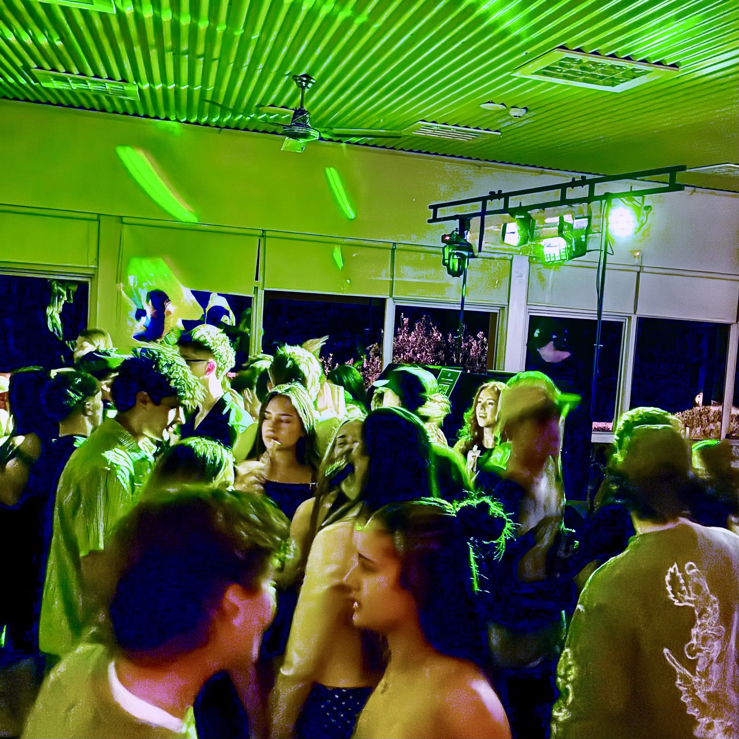People watching a presentation or exhibit in a room with a green illuminated ceiling and walls.