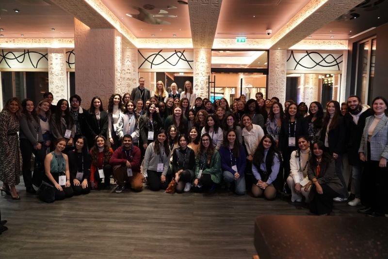 Group of diverse people posing for a photo in a well-lit hotel lobby or conference center.