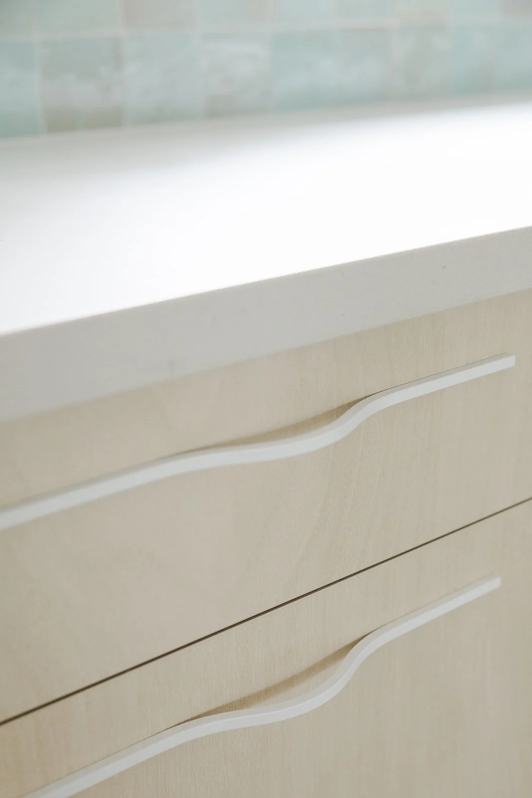 Close-up of a beige drawer cabinet with white curved handles, part of a modern furniture piece.