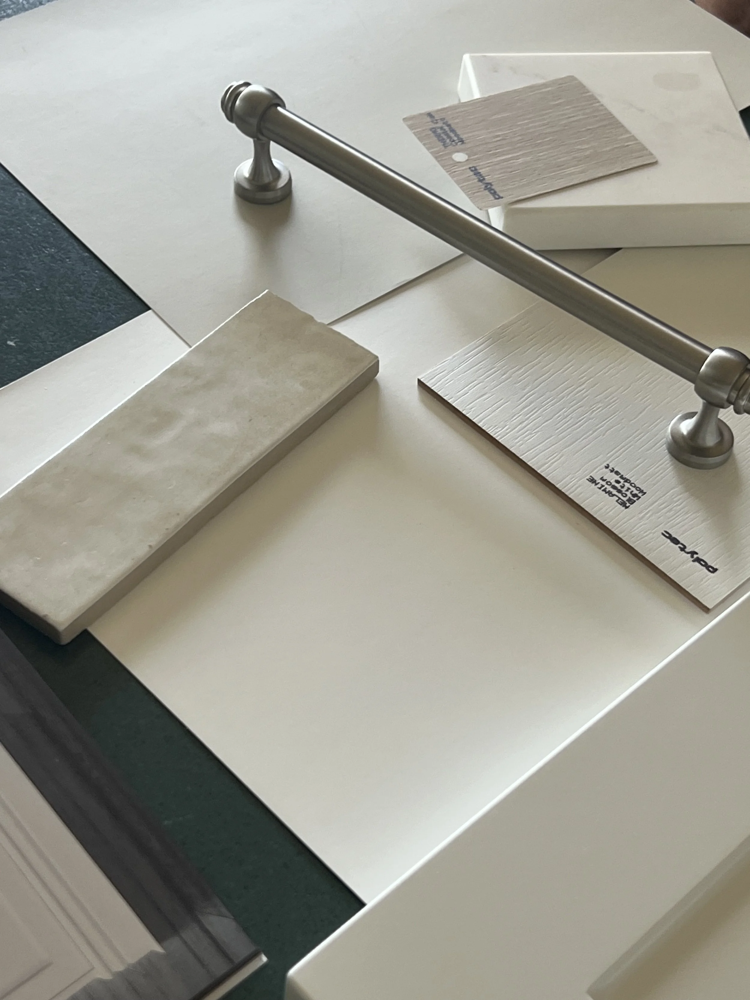 Sample tile samples and a silver door handle on a white countertop in a showroom.